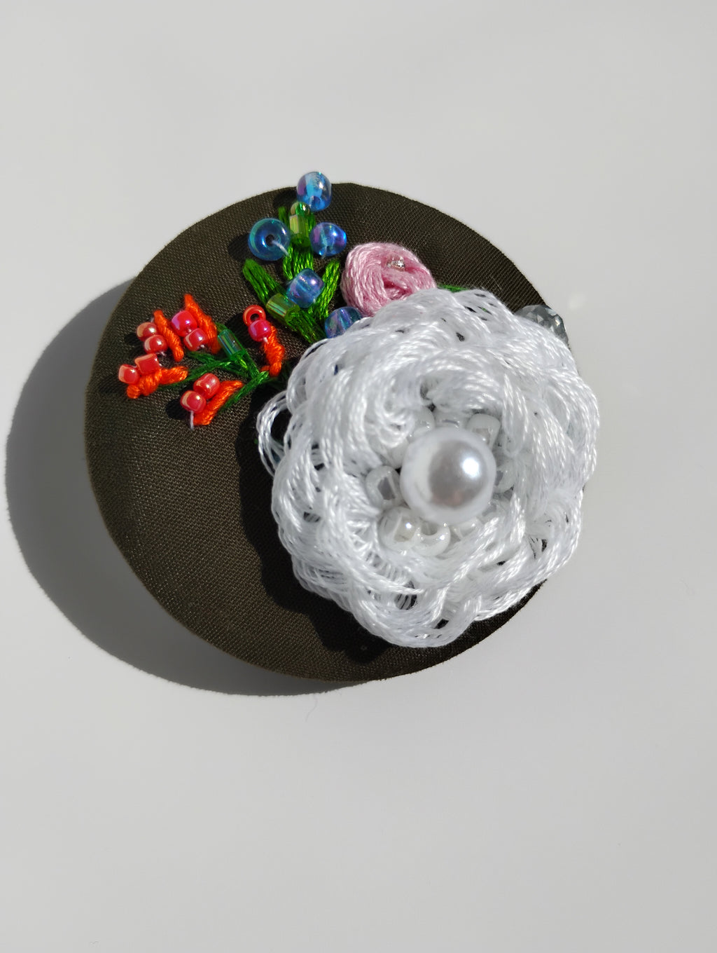 Decorative white flower brooch on olive background