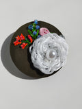 Decorative white flower brooch on olive background
