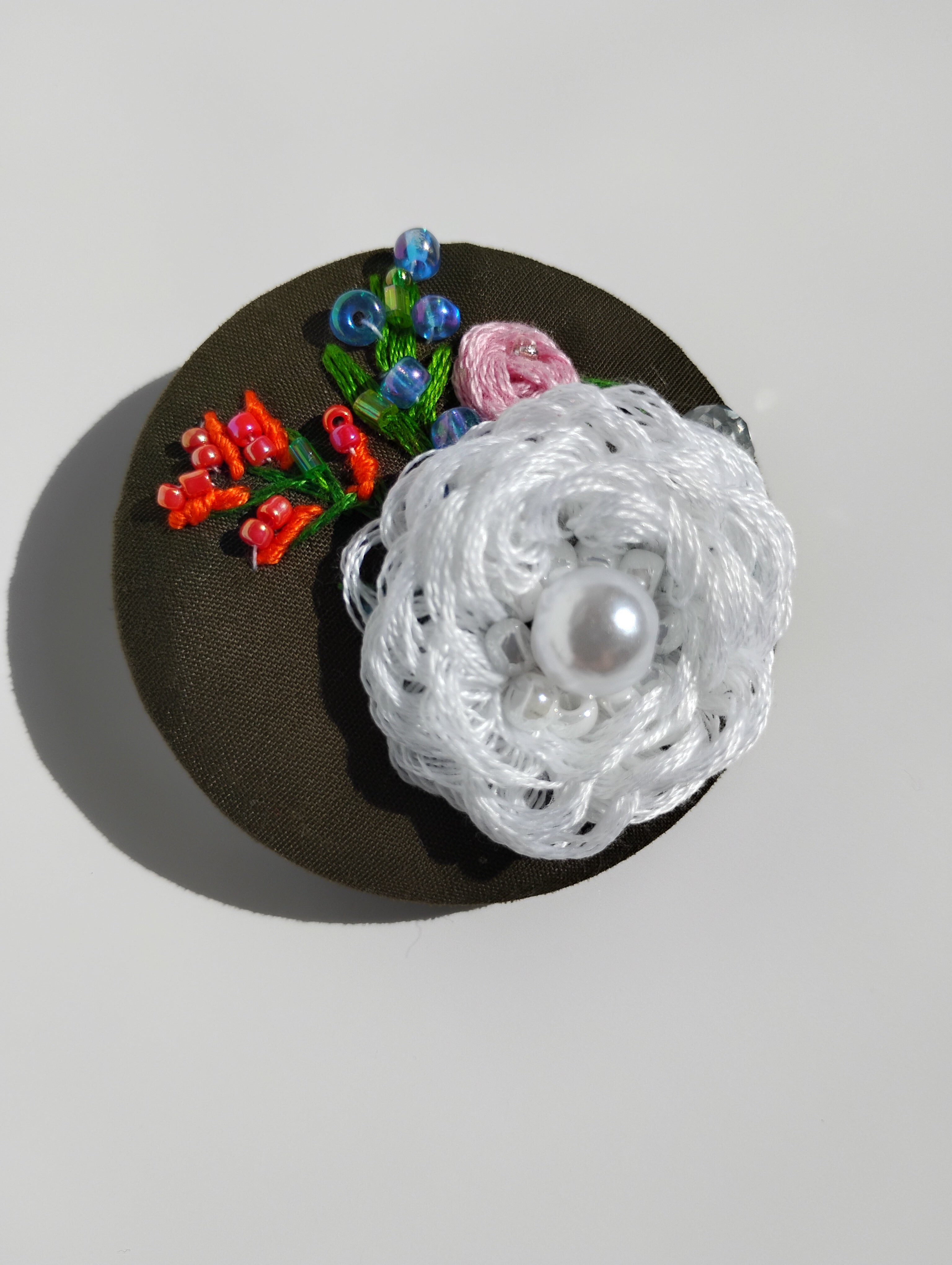 Decorative white flower brooch on olive background