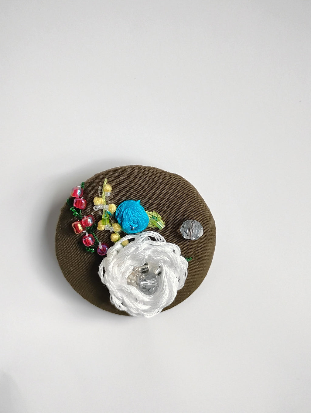 Decorative white flower brooch on olive background