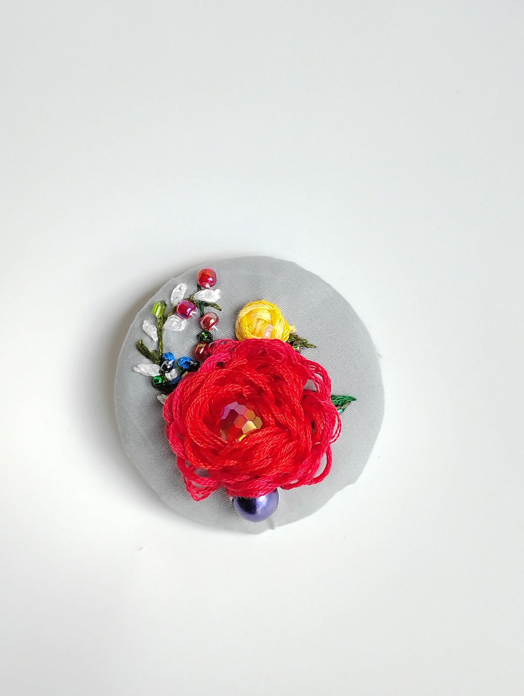 Decorative red flower brooch on grey background