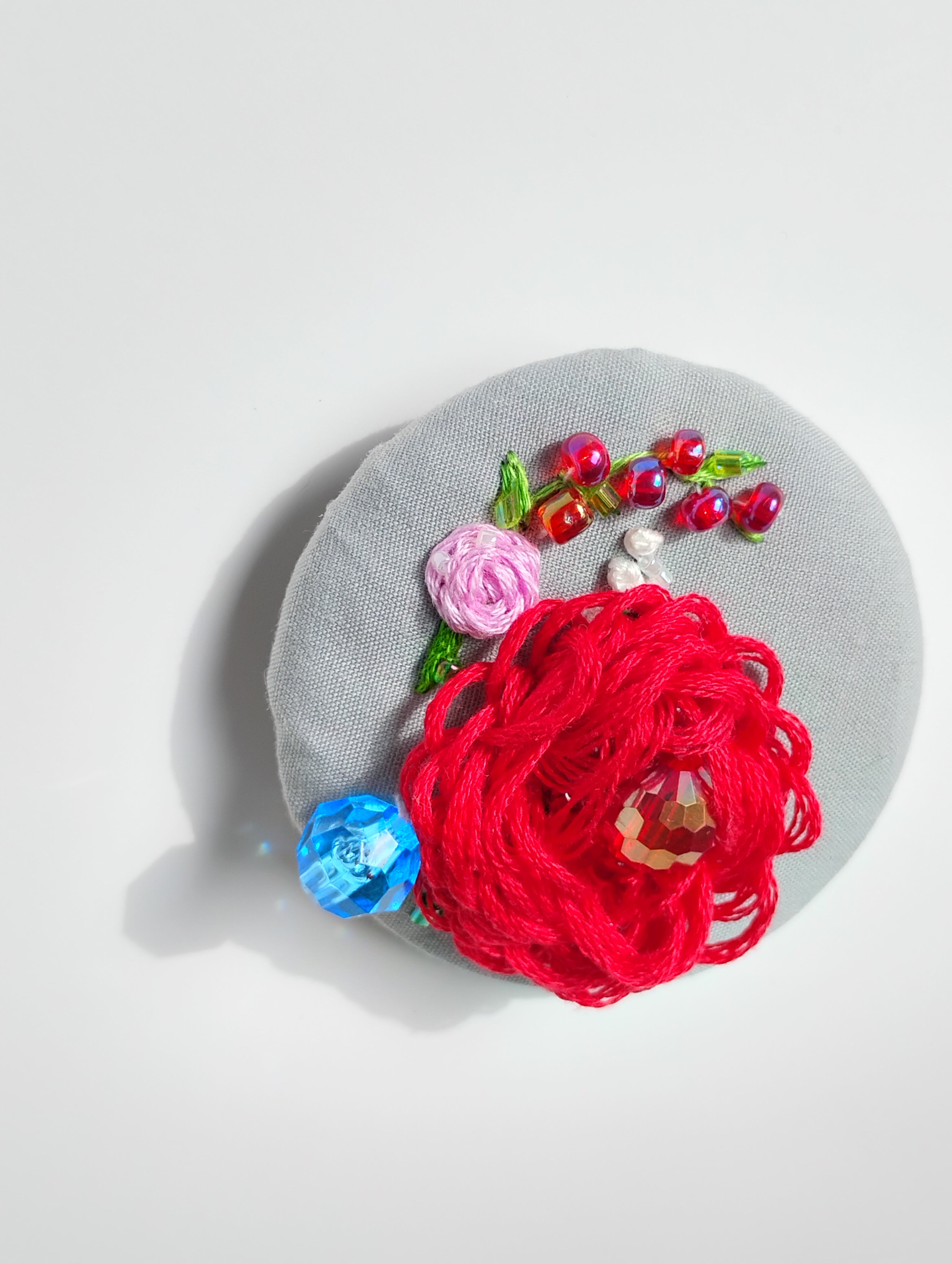 Decorative red flower brooch on grey background