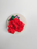 Decorative red flower brooch on cream background