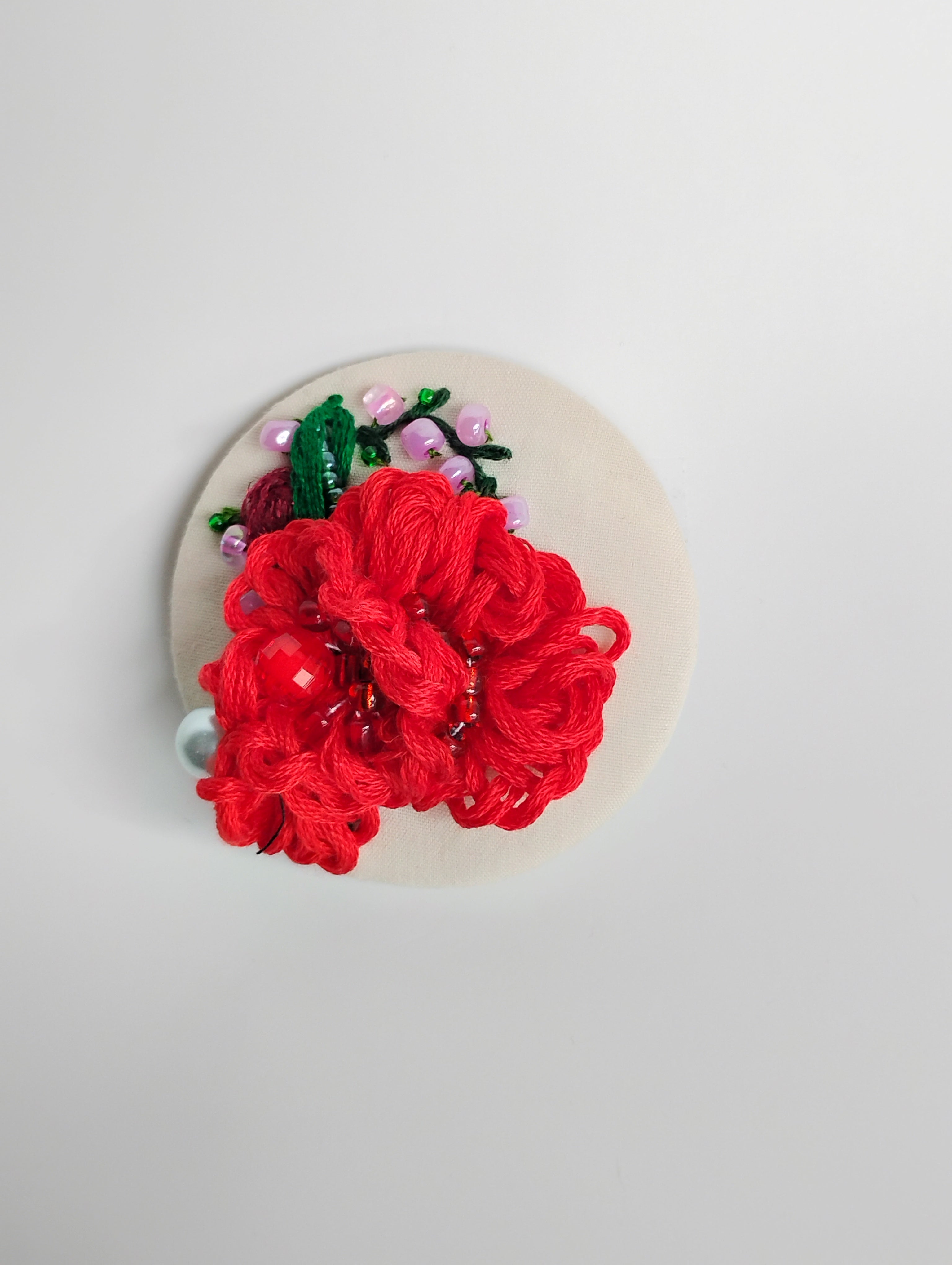 Decorative red flower brooch on cream background