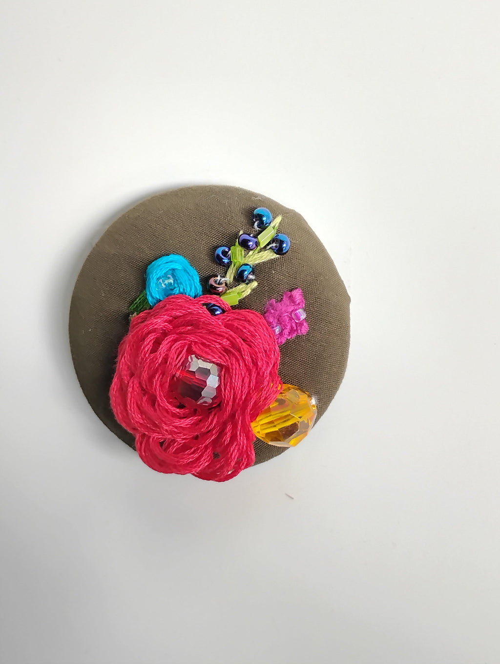 Decorative red flower brooch on olive background