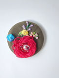 Decorative red flower brooch on olive background