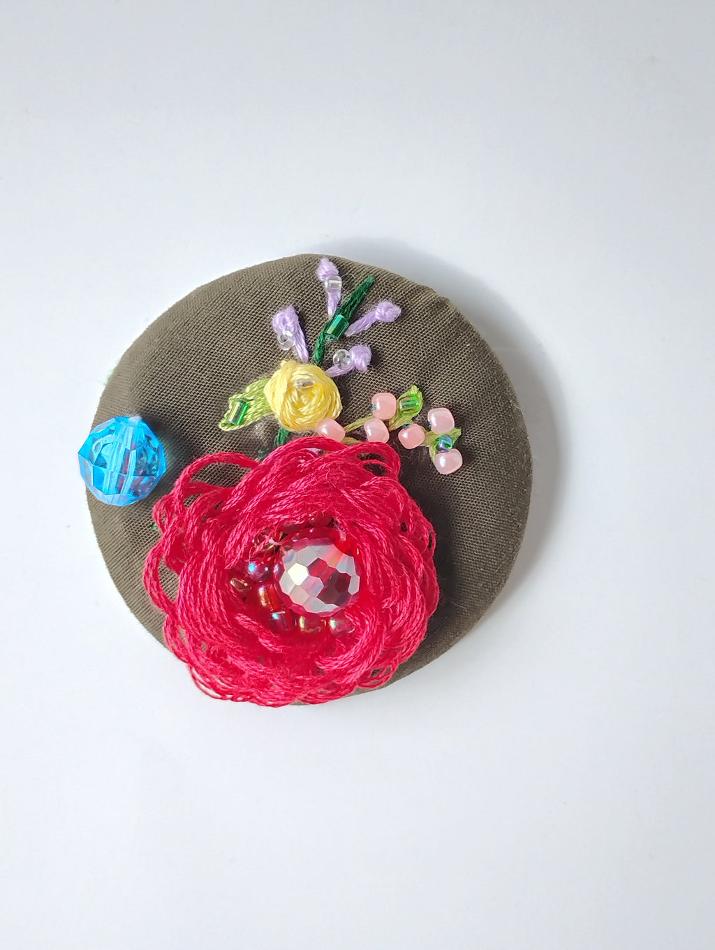 Decorative red flower brooch on olive background