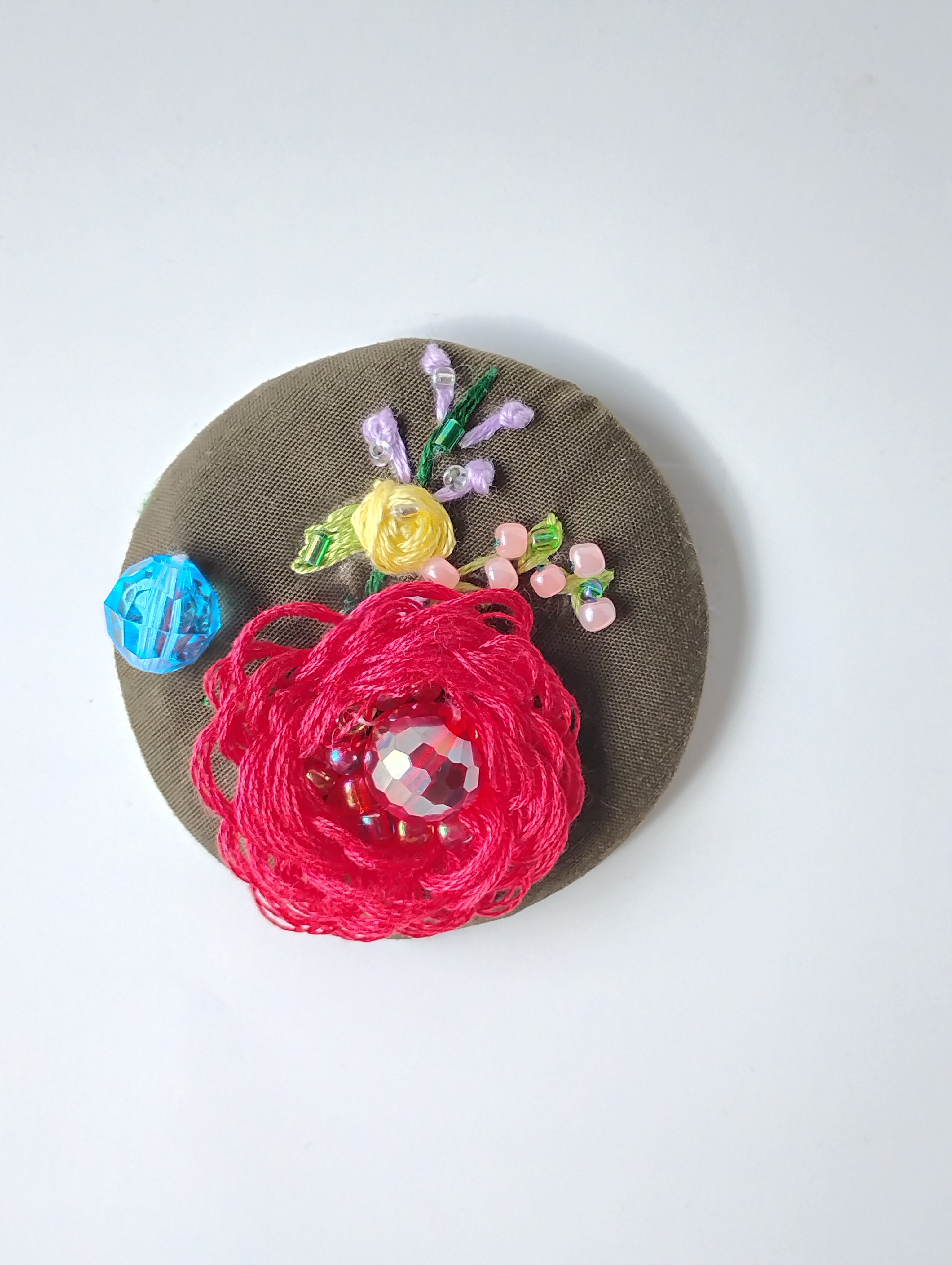 Decorative red flower brooch on olive background