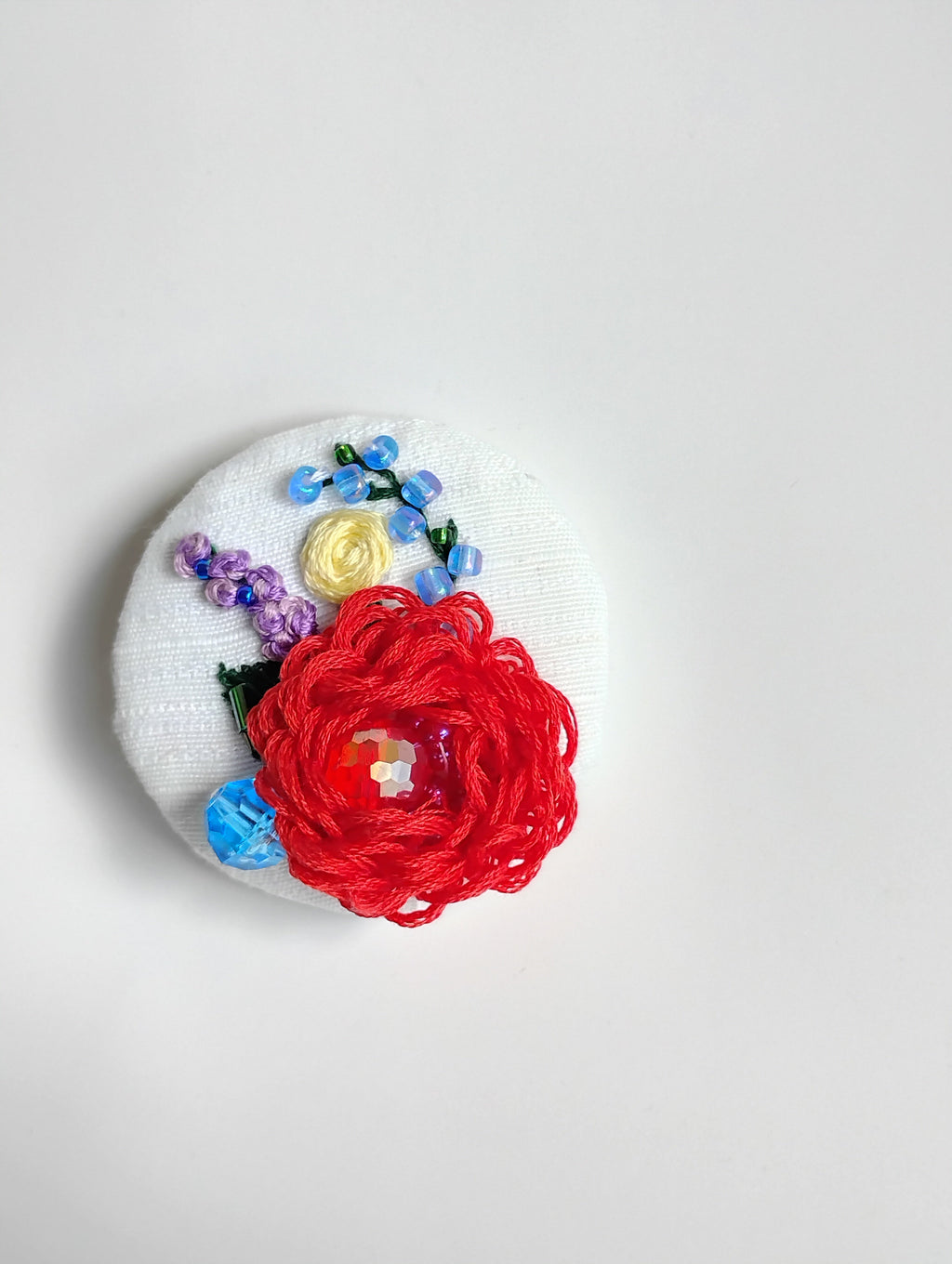 Decorative red flower brooch on white textured background