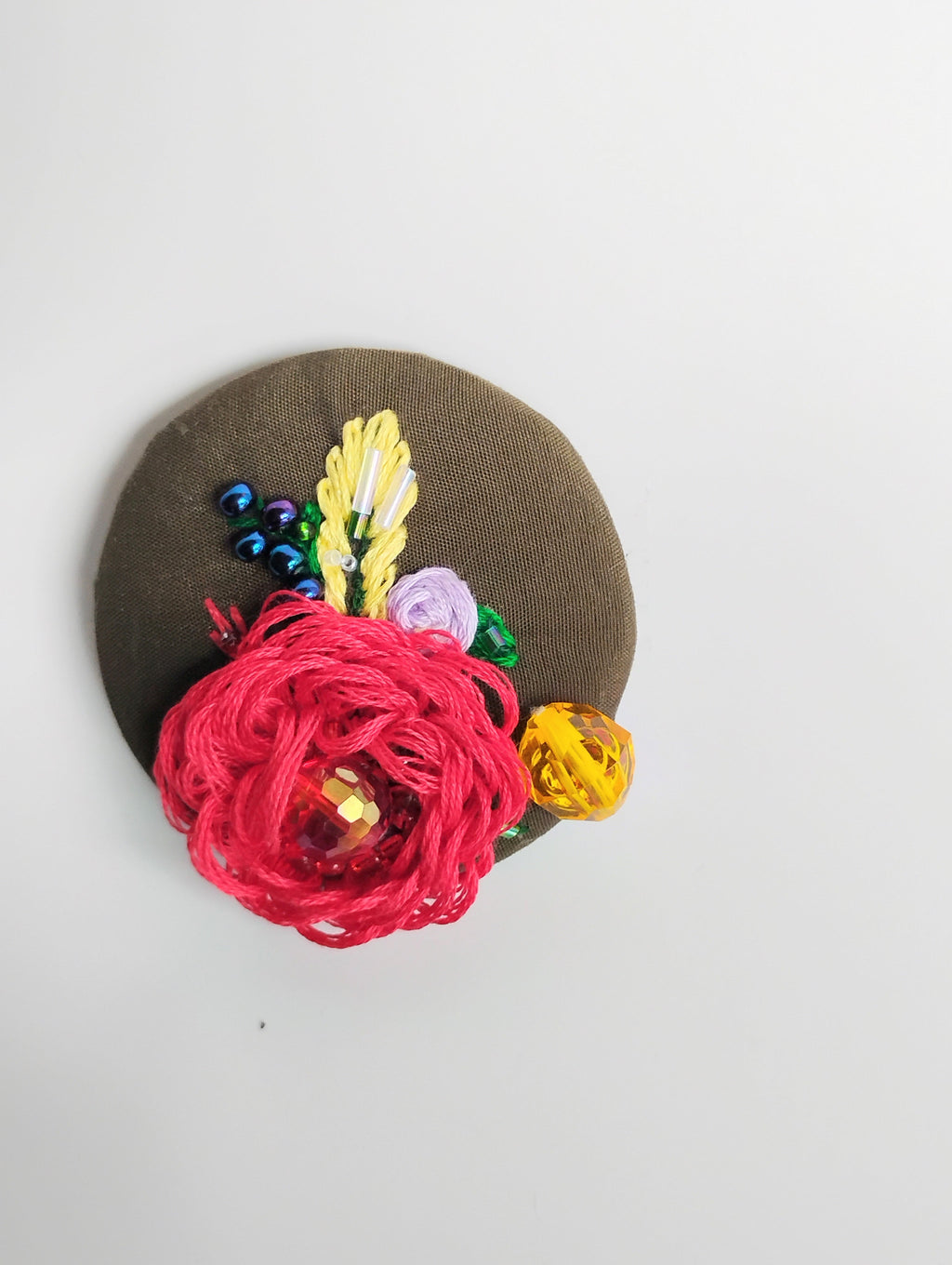 Decorative red flower brooch on olive background