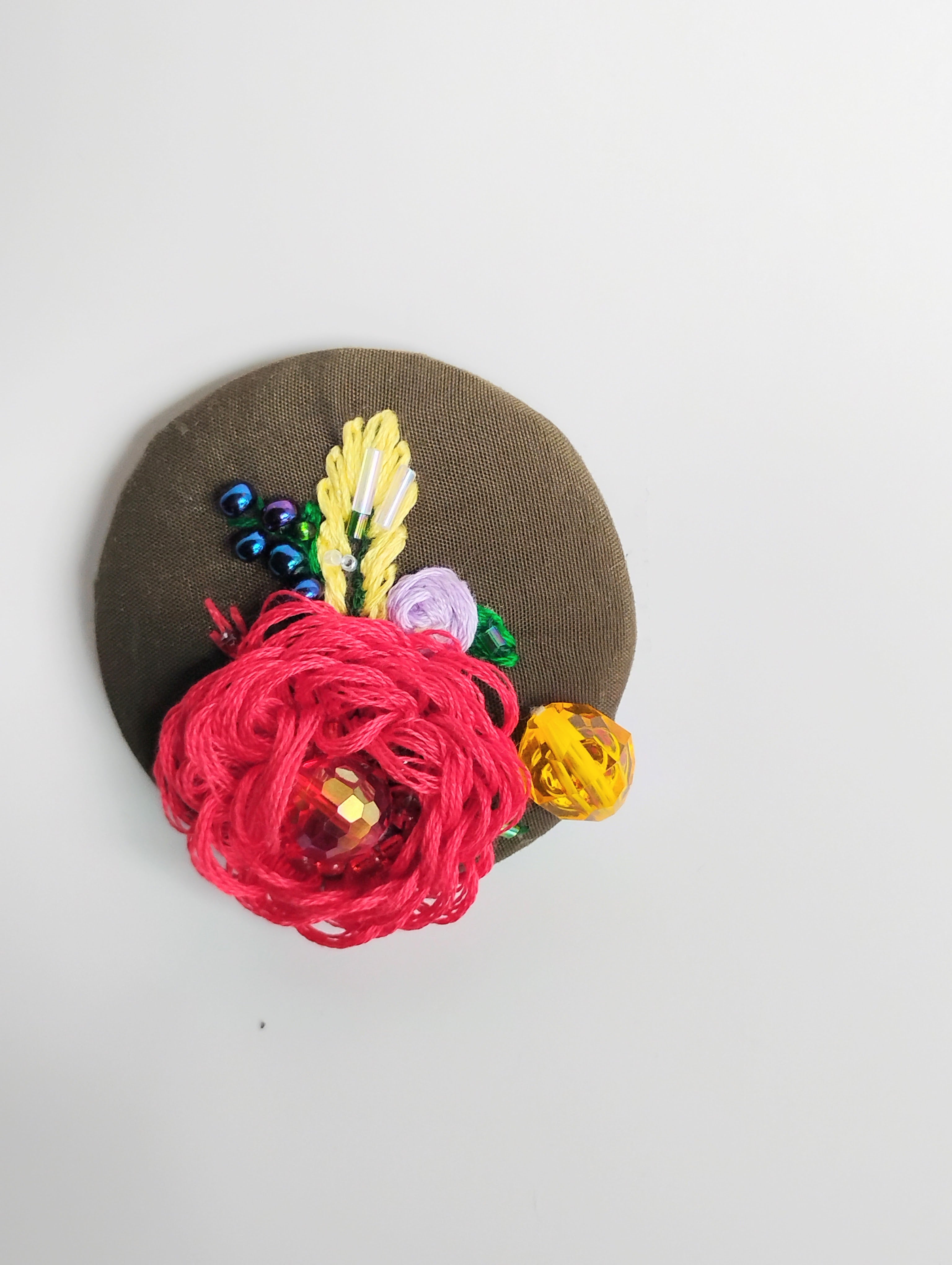 Decorative red flower brooch on olive background