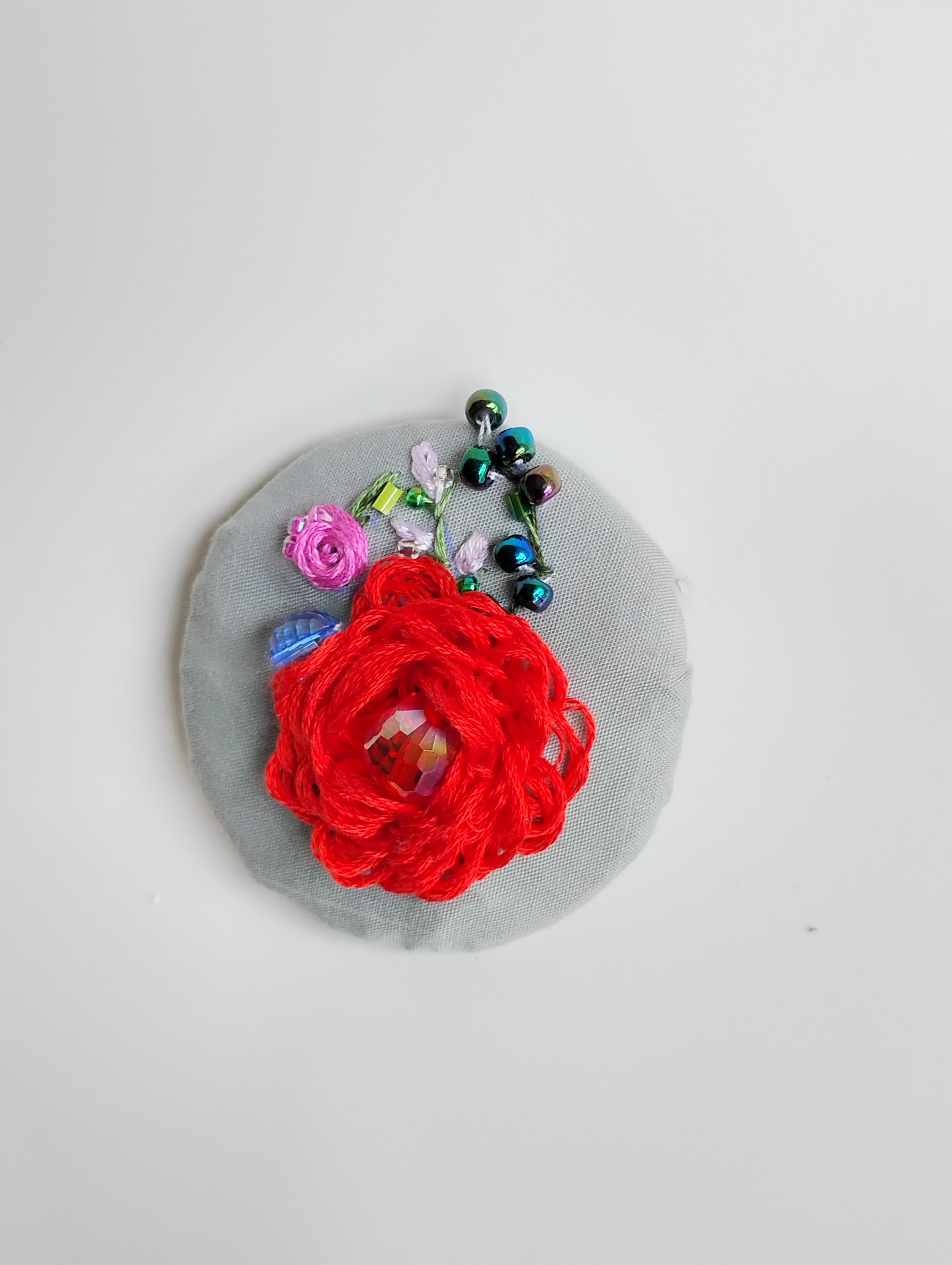 Decorative red flower brooch on grey background