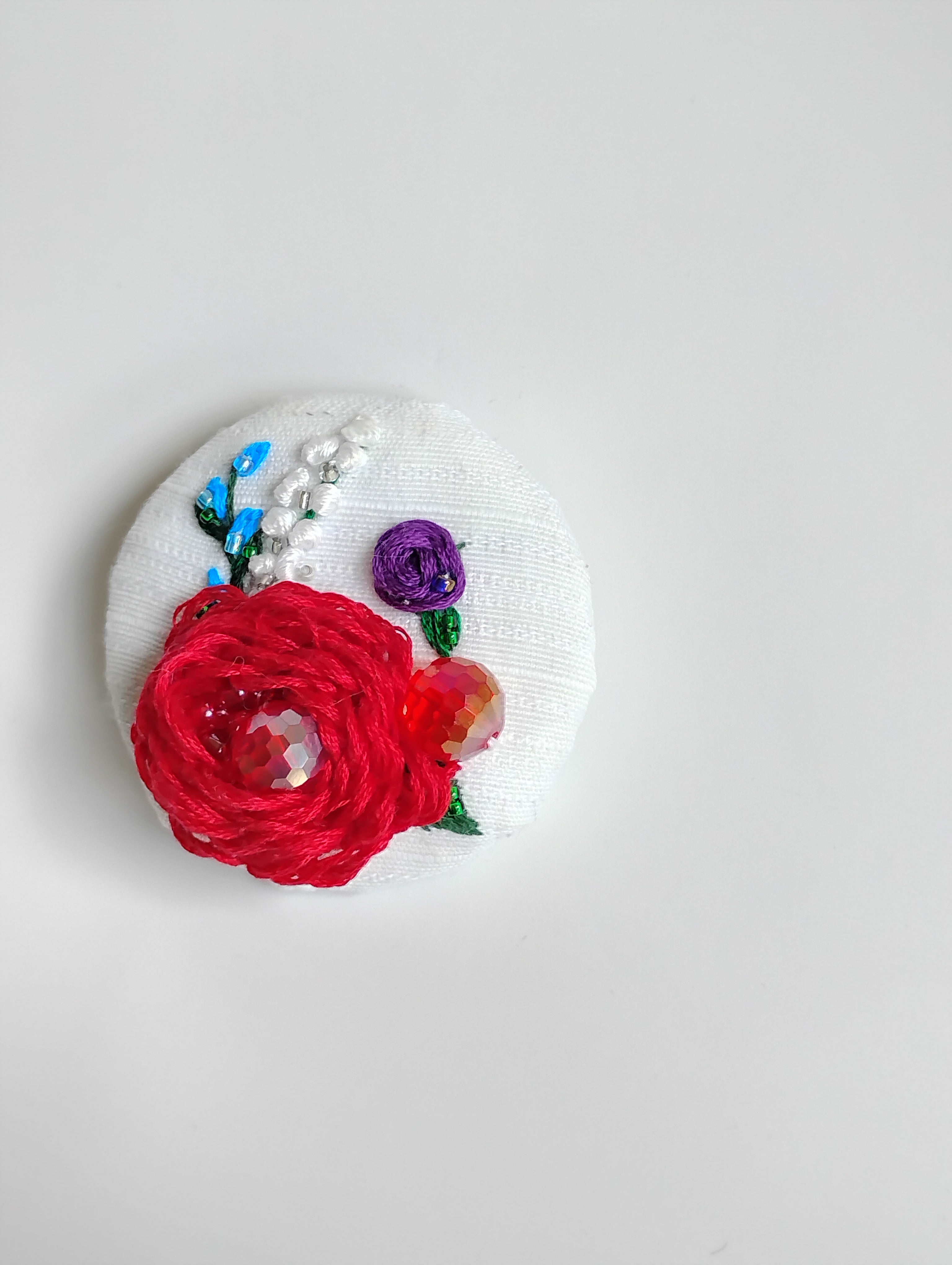Decorative red flower brooch on white textured background