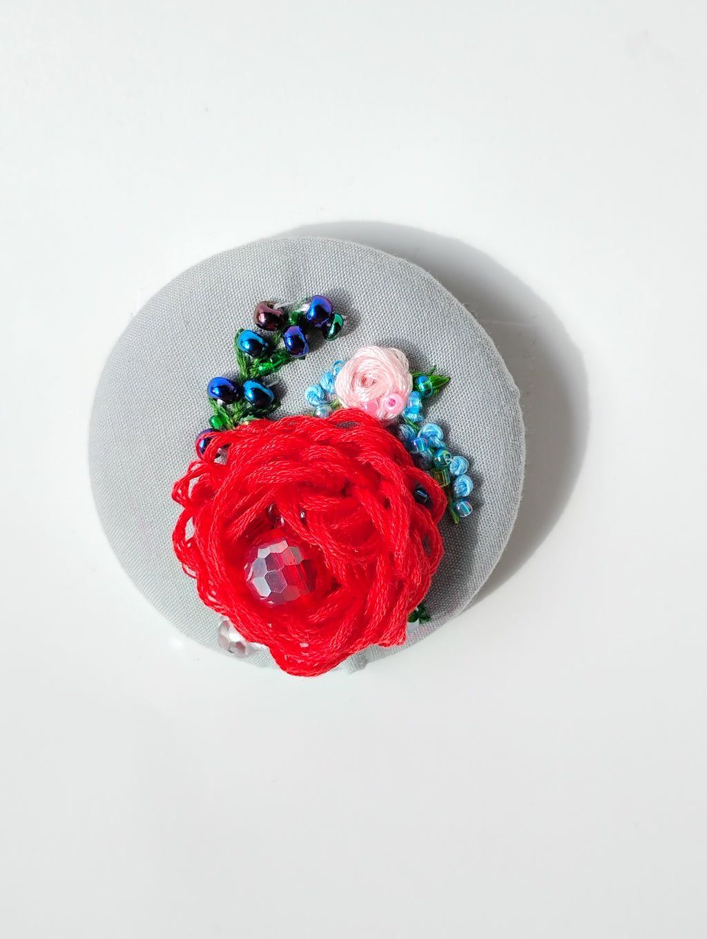 Decorative red flower brooch on grey background