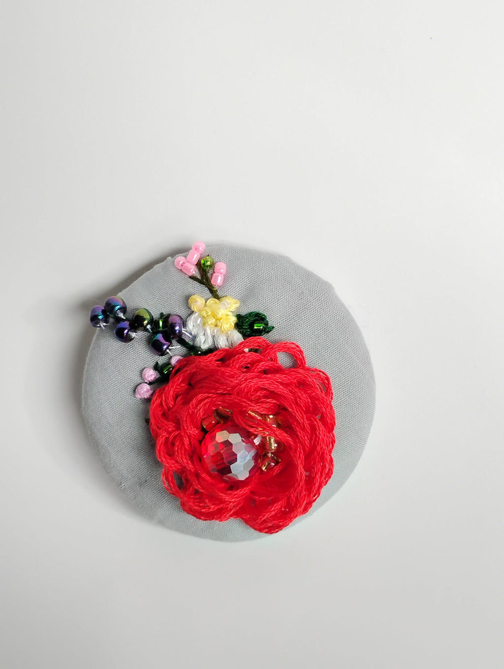 Decorative red flower brooch on grey background