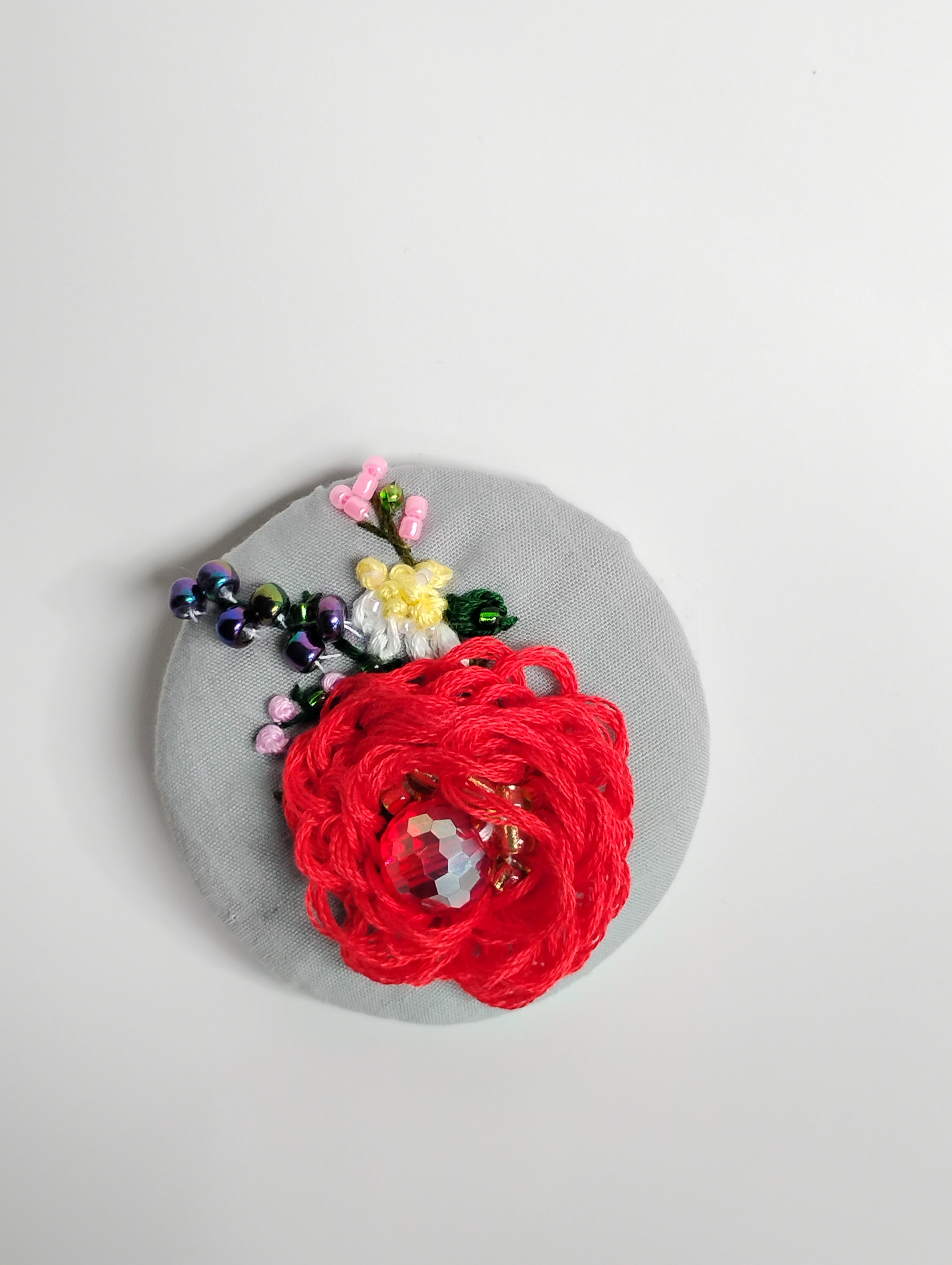 Decorative red flower brooch on grey background