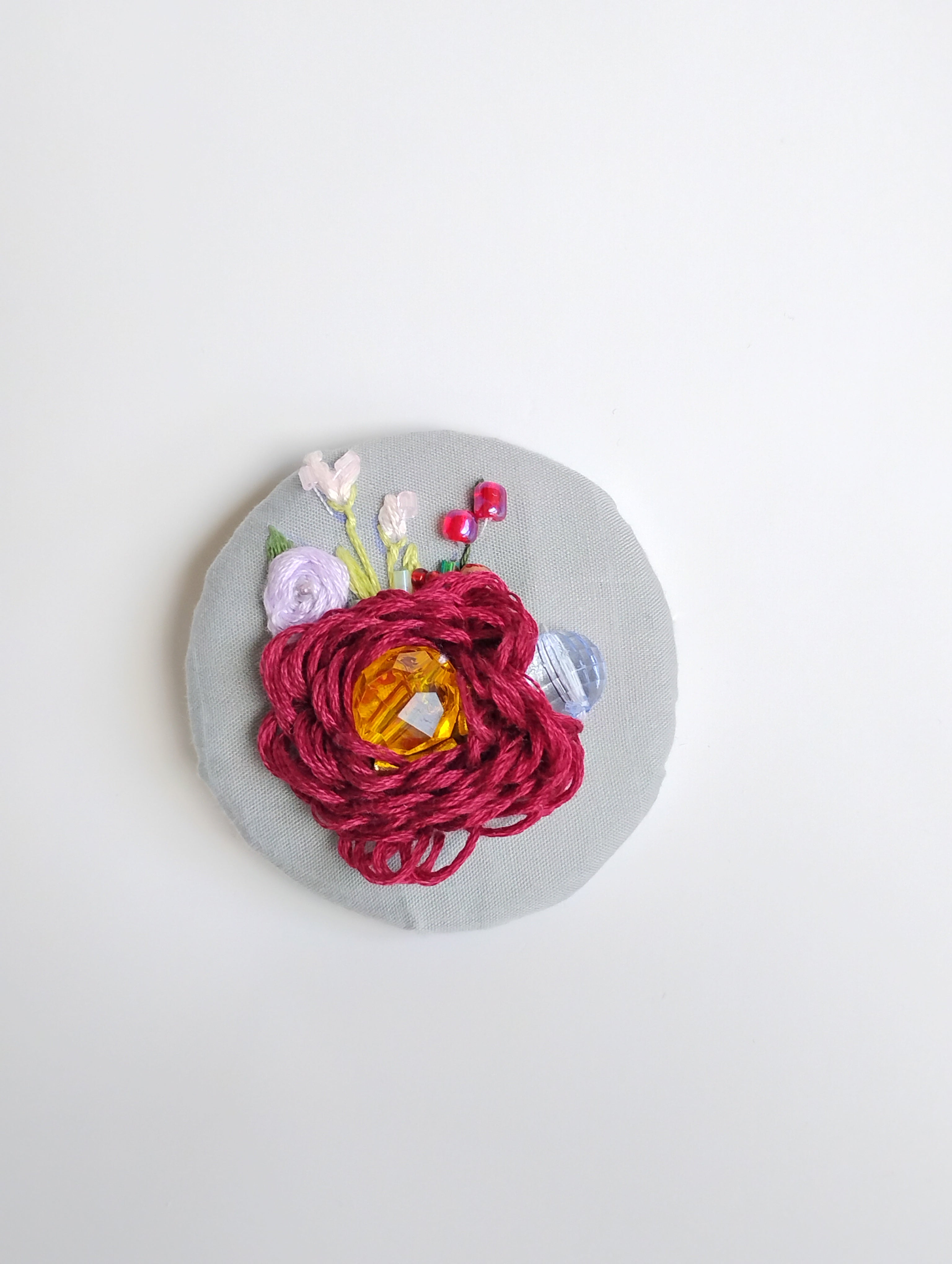 Decorative burgundy flower brooch on grey background