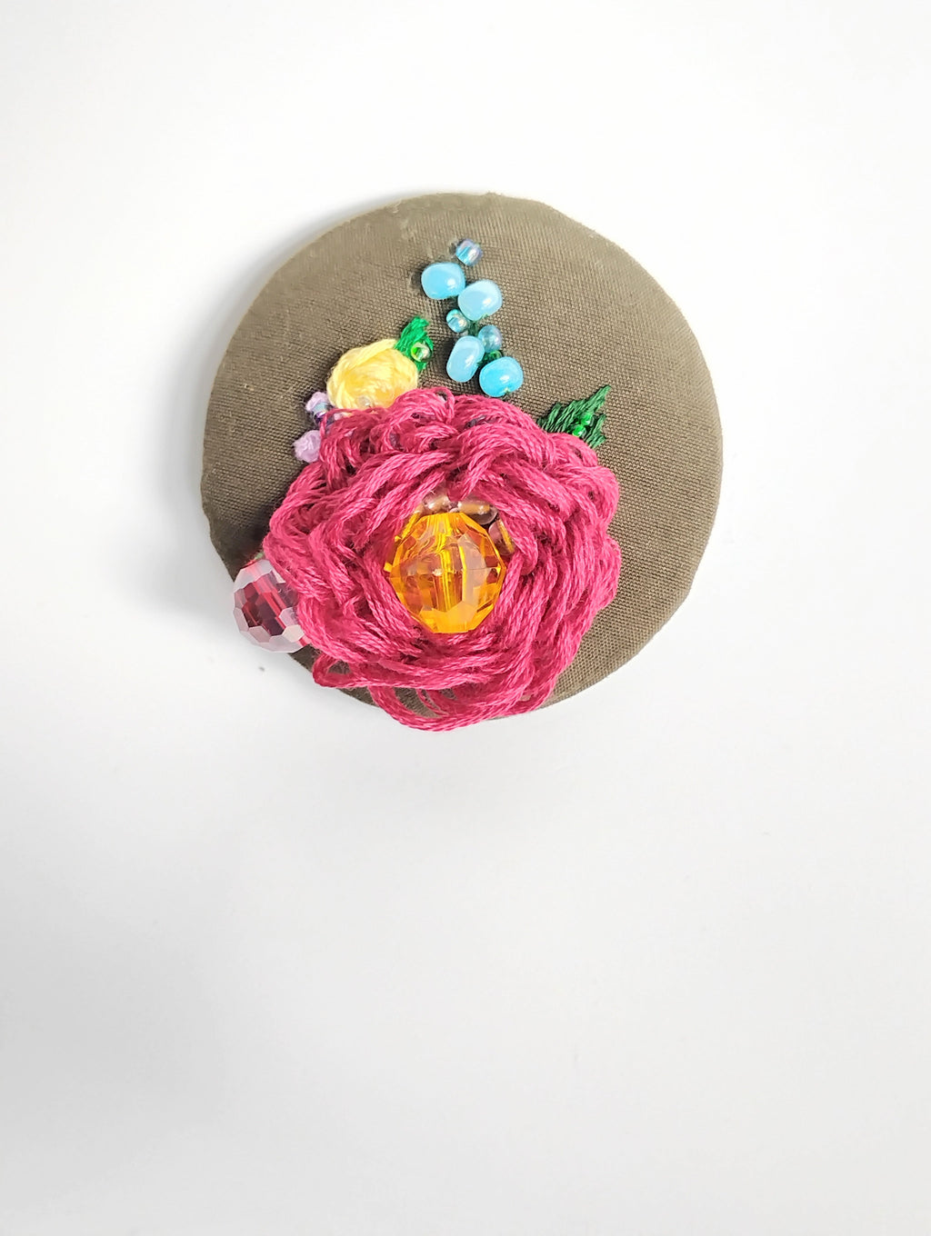 Decorative burgundy flower brooch on olive background