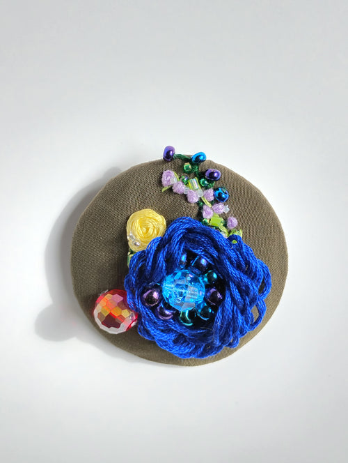 Decorative blue flower brooch on olive background