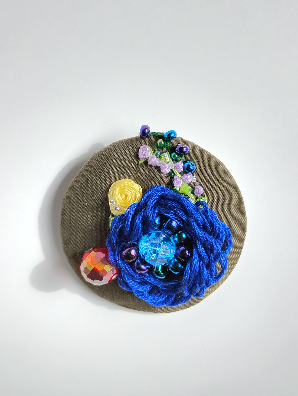 Decorative blue flower brooch on olive background