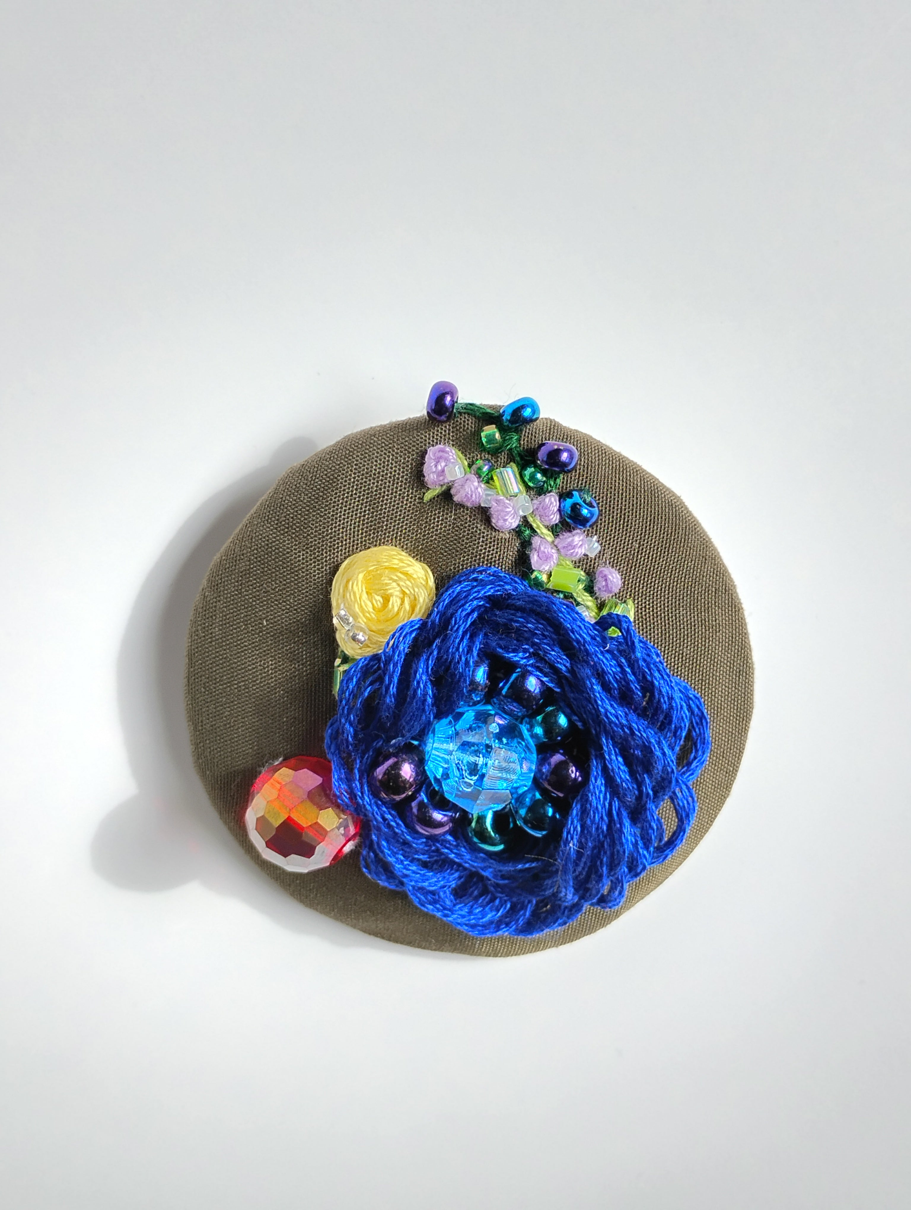 Decorative blue flower brooch on olive background