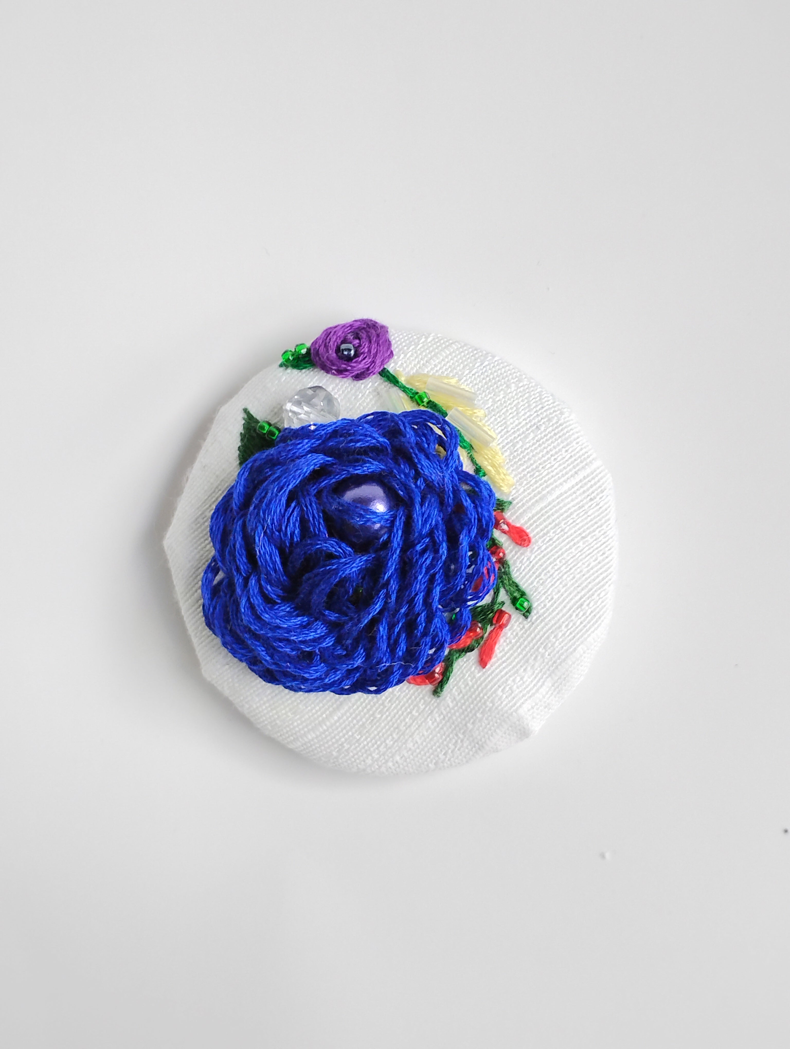 Decorative blue flower brooch on white textured background