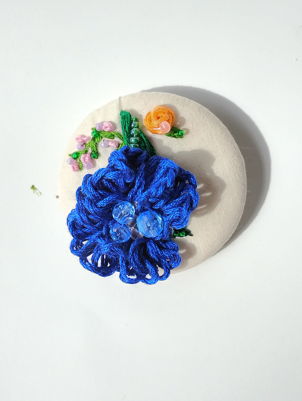 Decorative blue flower brooch on cream background