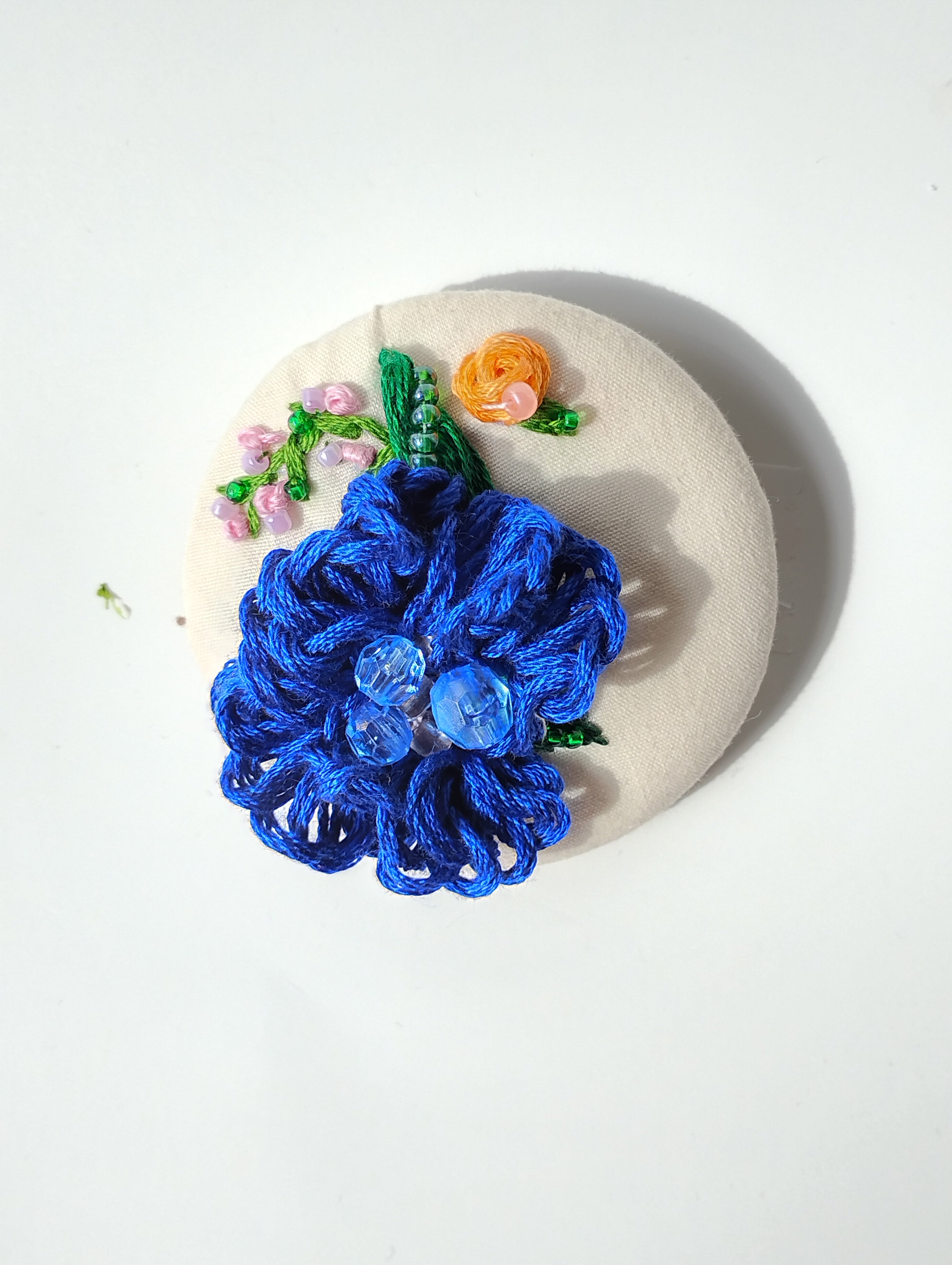 Decorative blue flower brooch on cream background