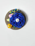 Decorative blue flower brooch on olive background