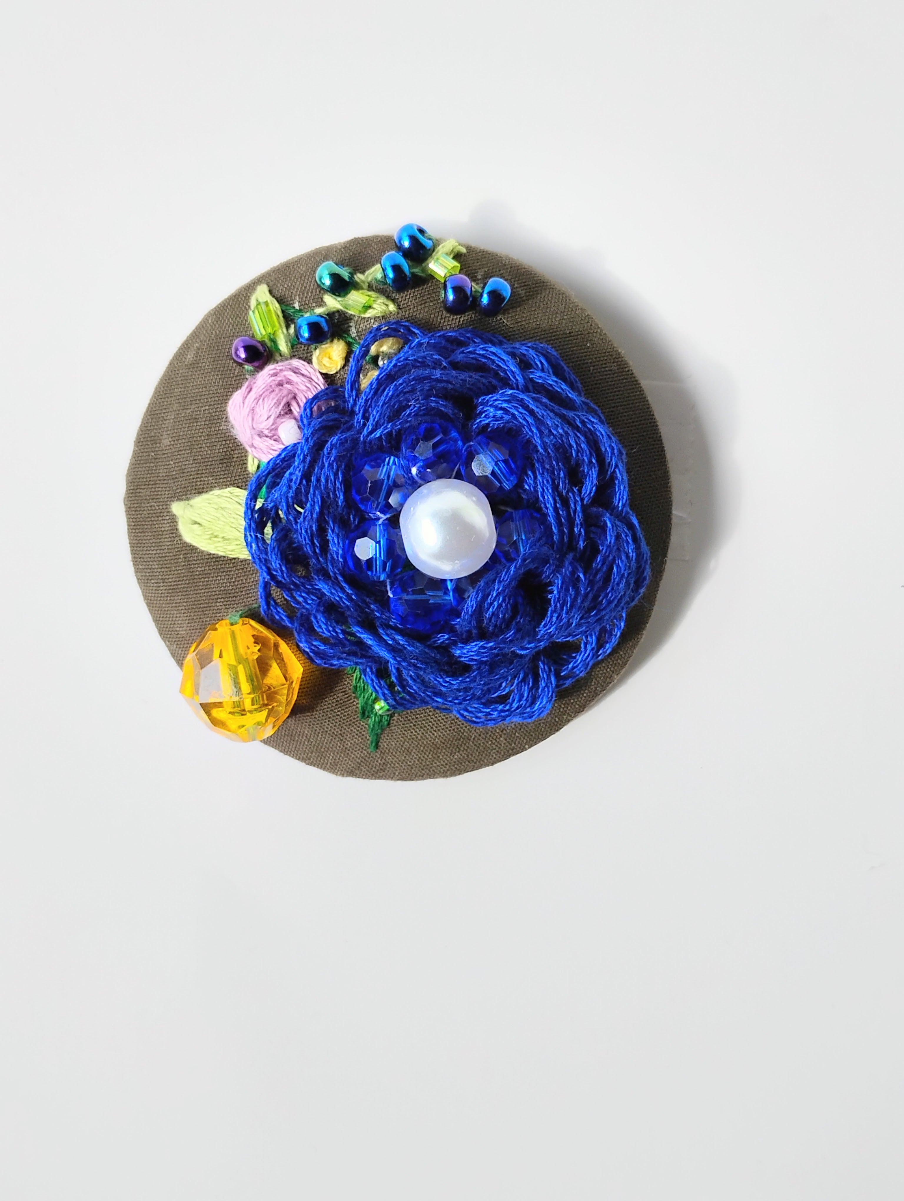 Decorative blue flower brooch on olive background