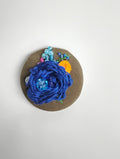 Decorative blue flower brooch on olive background