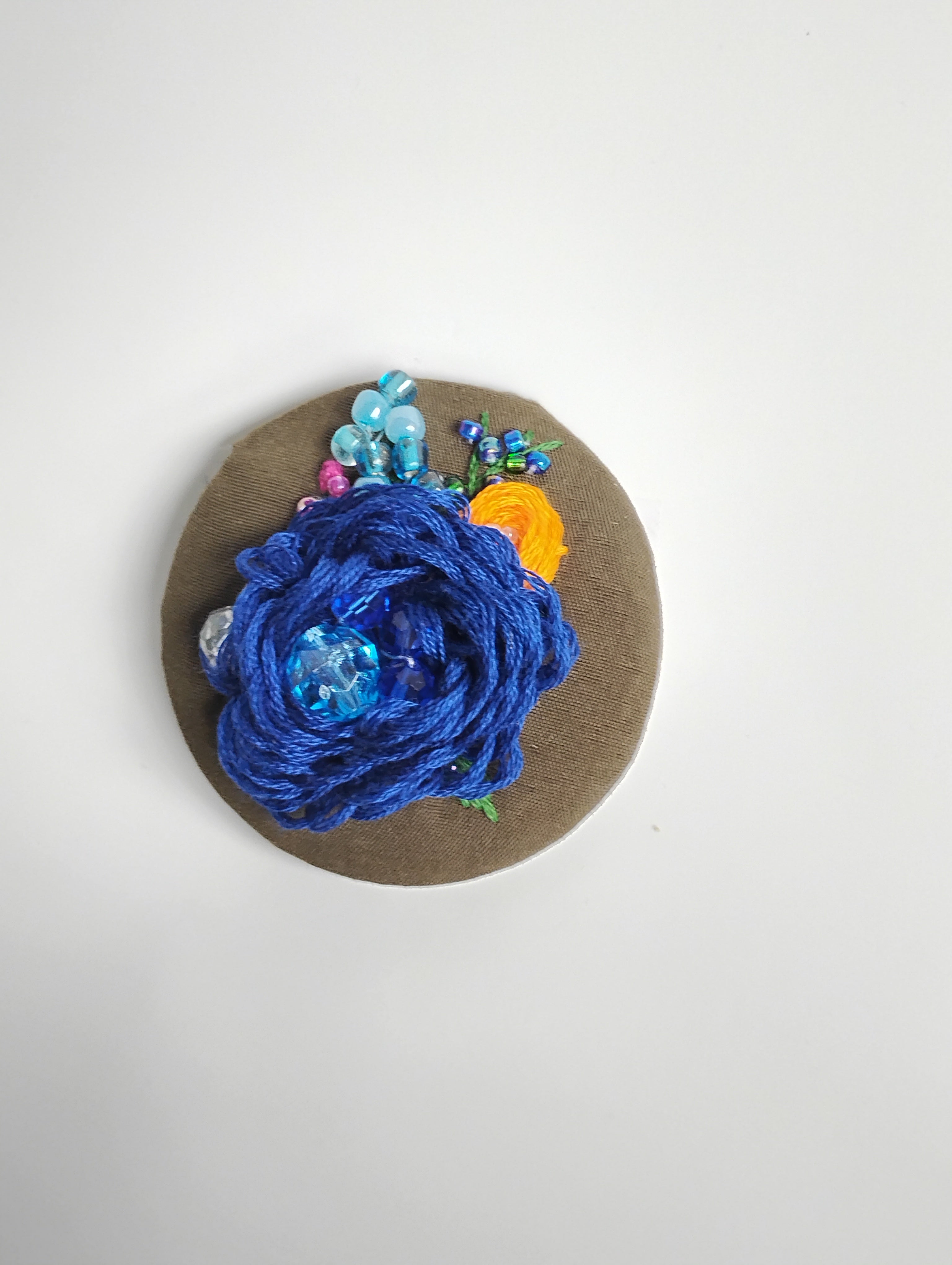 Decorative blue flower brooch on olive background