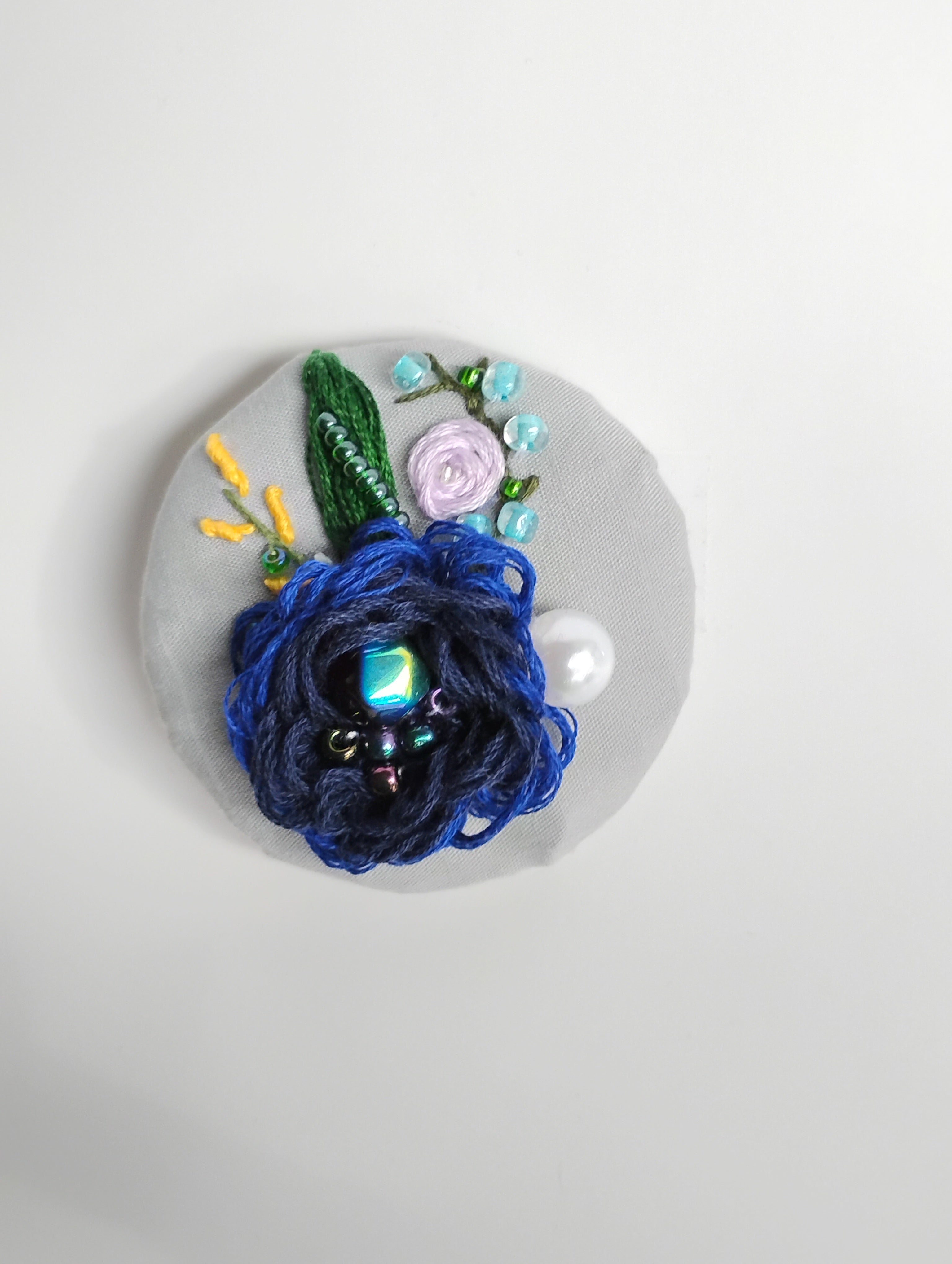 Decorative blue flower brooch on grey background
