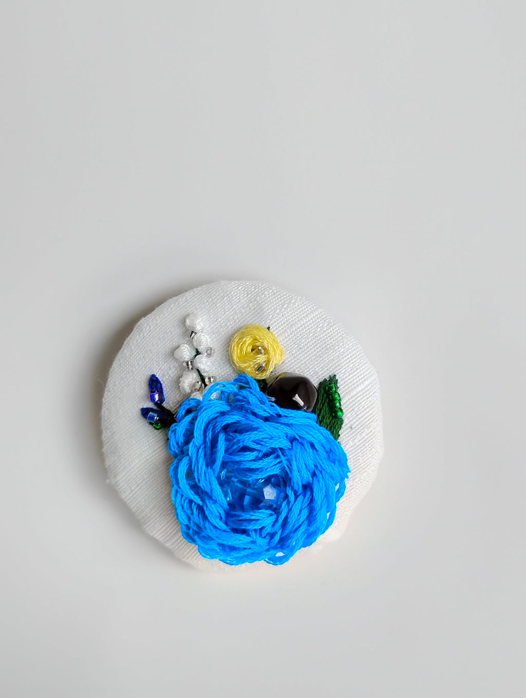 Decorative blue flower brooch on white textured background