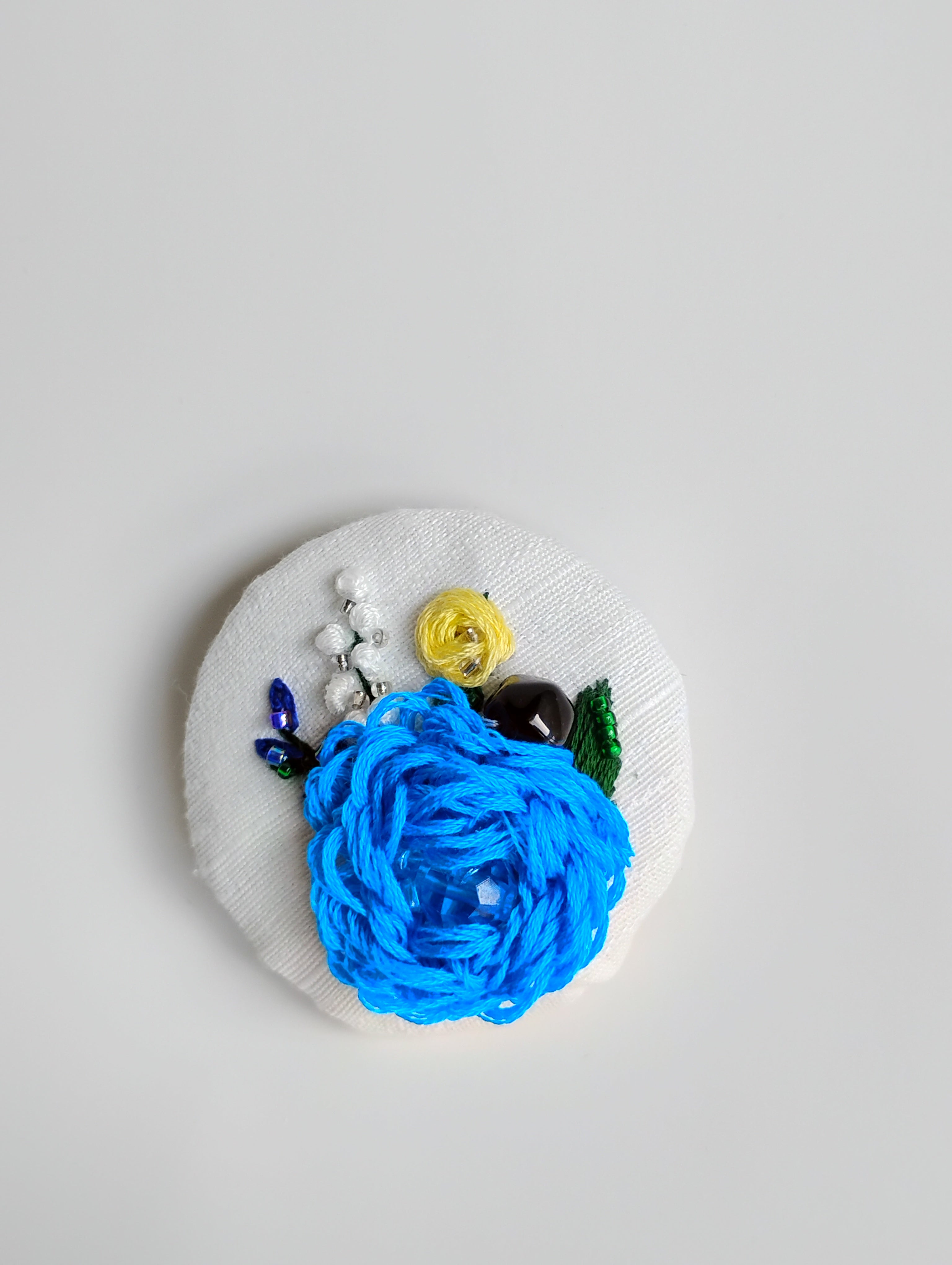 Decorative blue flower brooch on white textured background