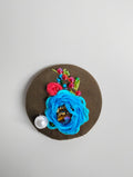 Decorative blue flower brooch on olive background