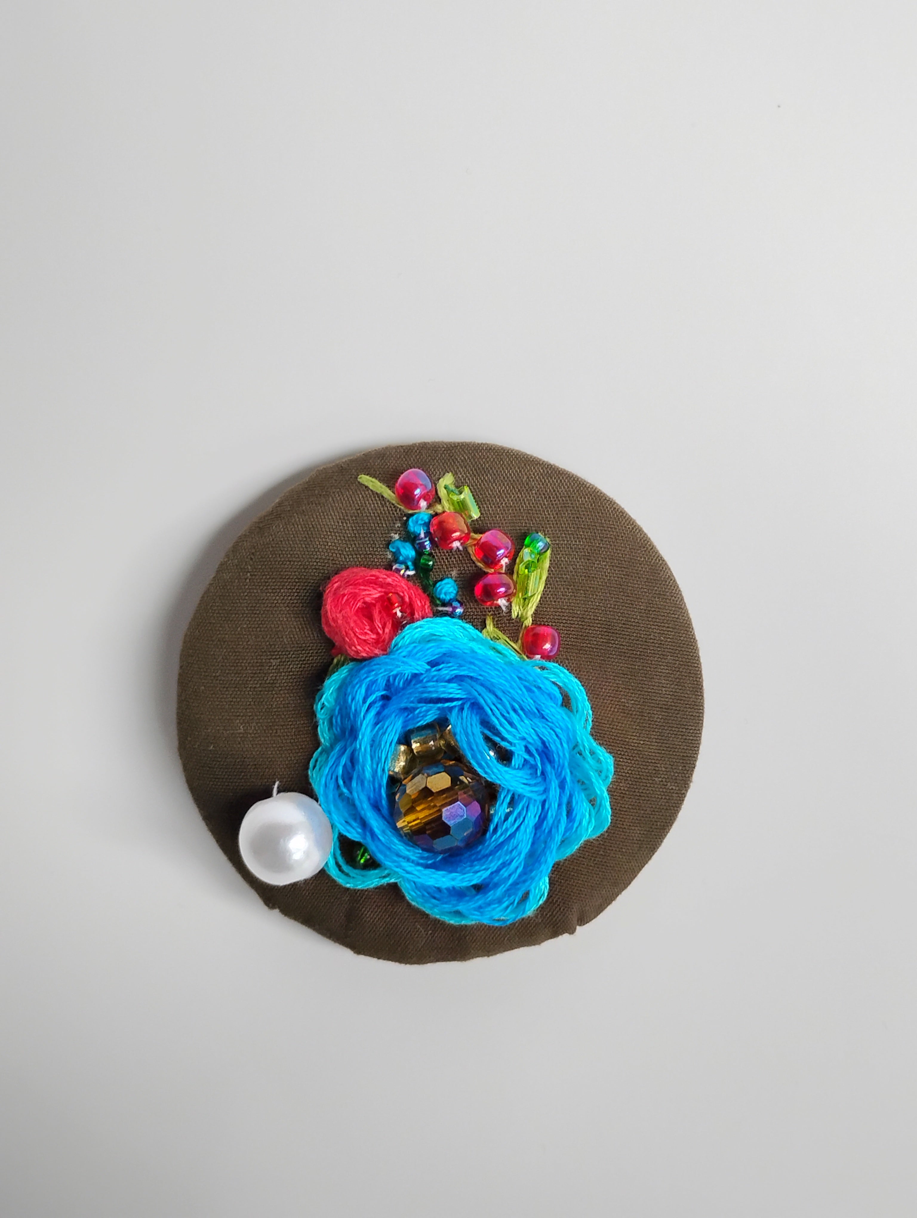 Decorative blue flower brooch on olive background