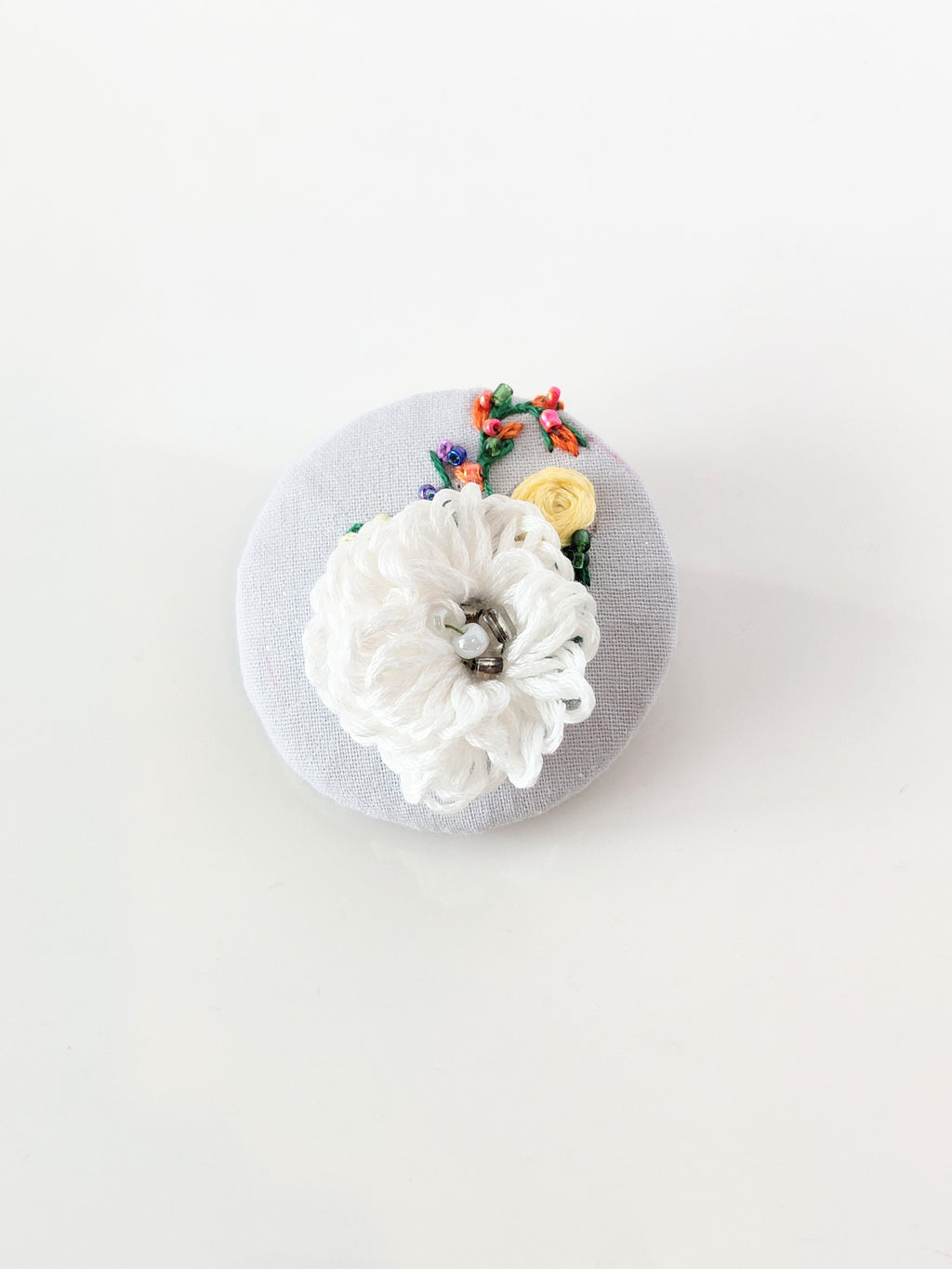 Decorative white flower brooch on grey background