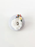 Decorative white flower brooch on grey background