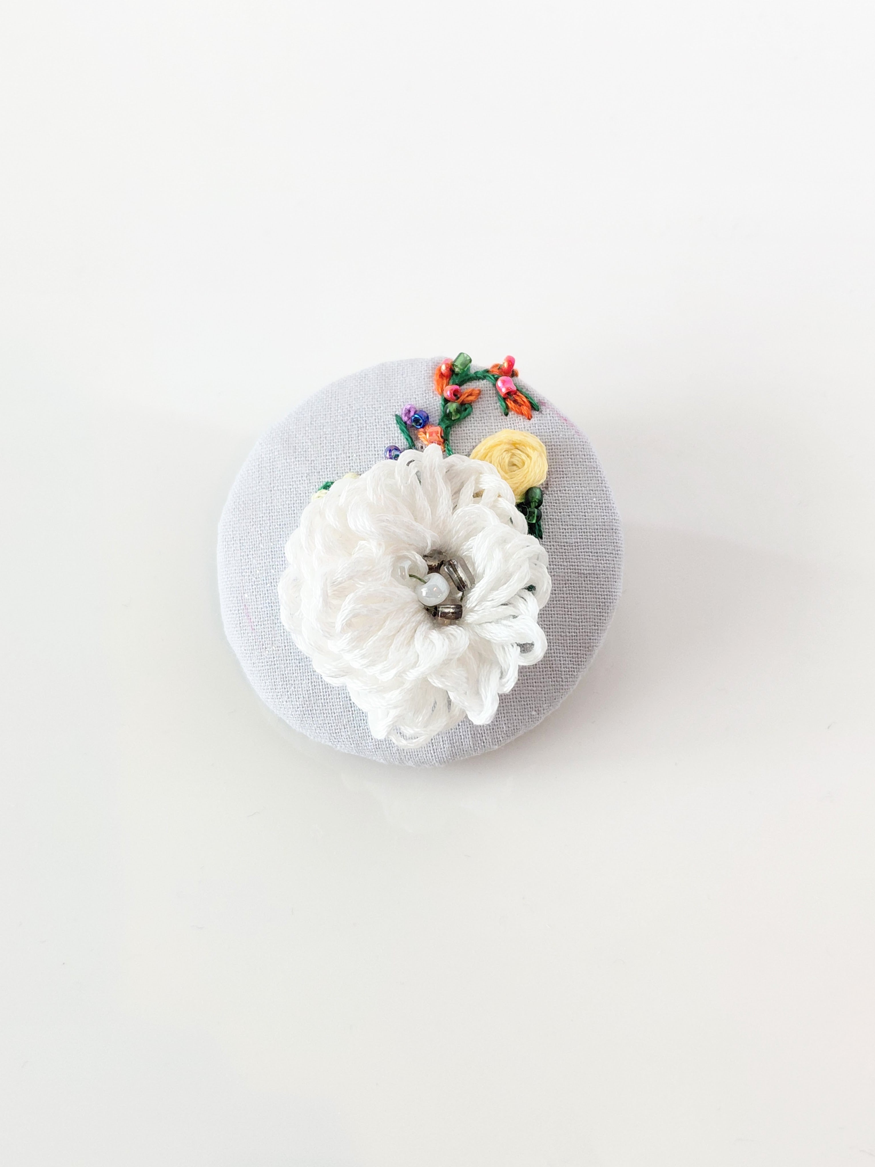 Decorative white flower brooch on grey background