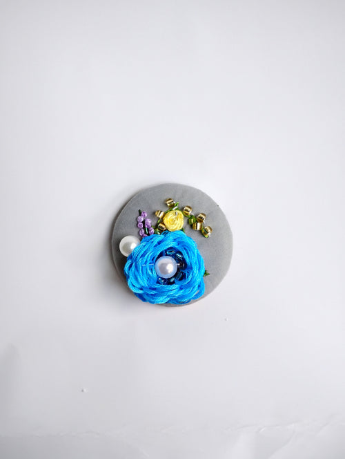 Decorative blue flower brooch on grey background