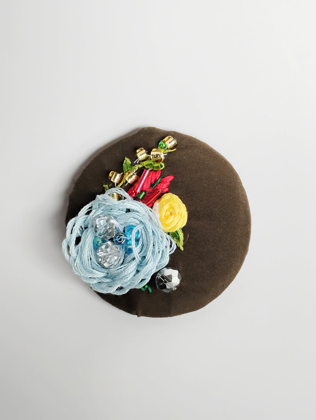 Decorative blue flower brooch on olive background