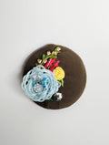 Decorative blue flower brooch on olive background