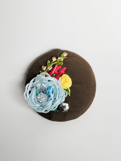 Decorative blue flower brooch on olive background