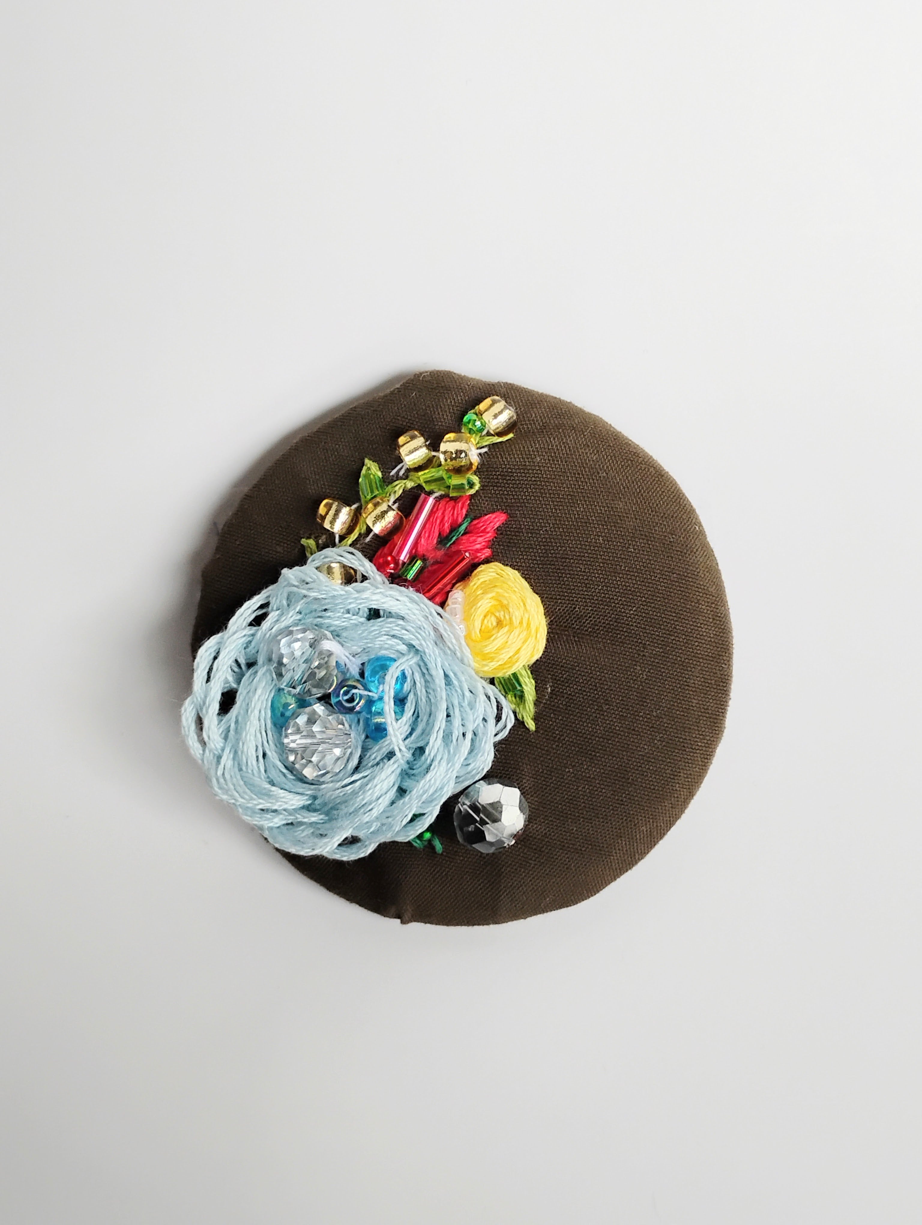 Decorative blue flower brooch on olive background