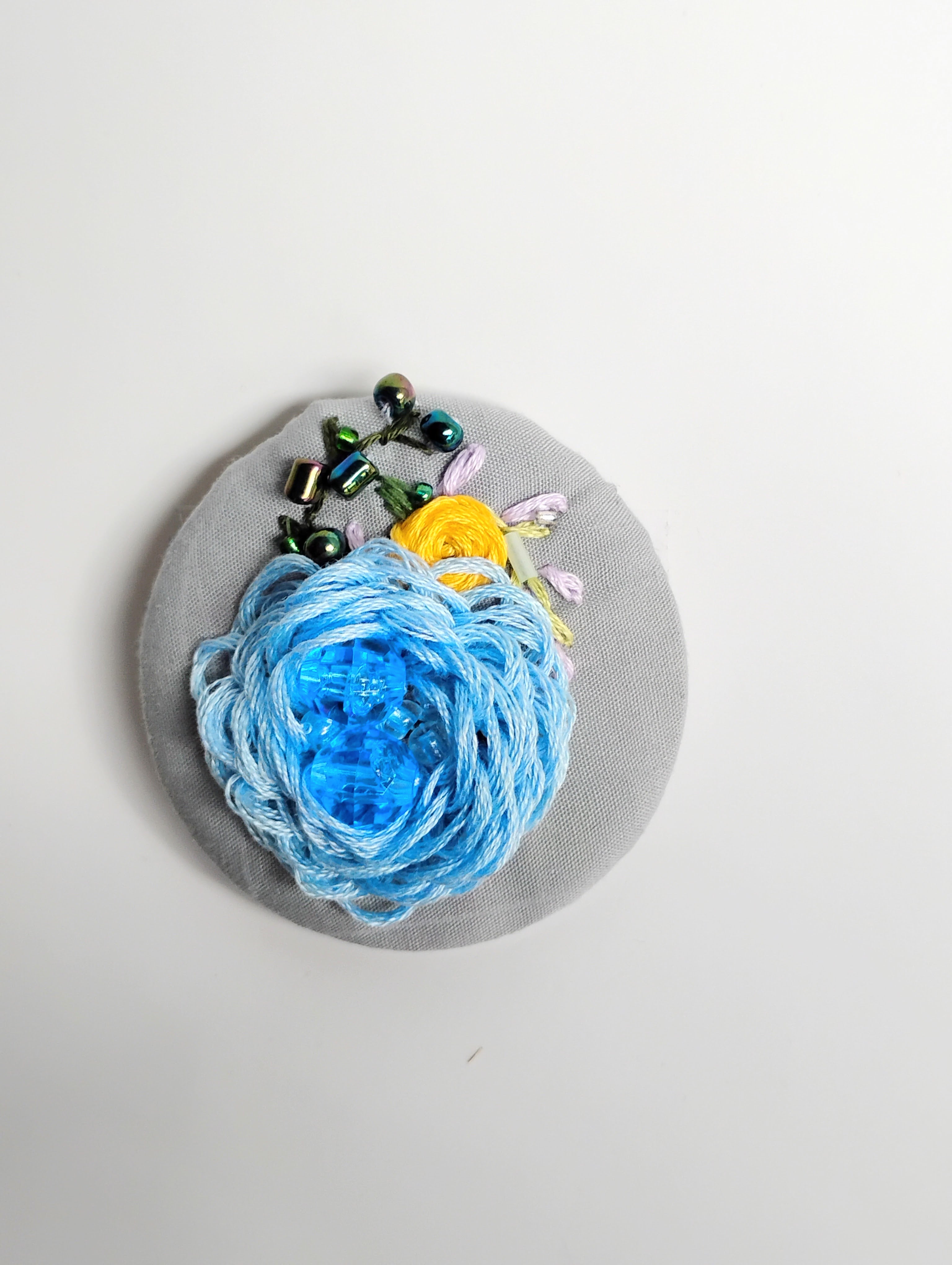 Decorative blue flower brooch on grey background