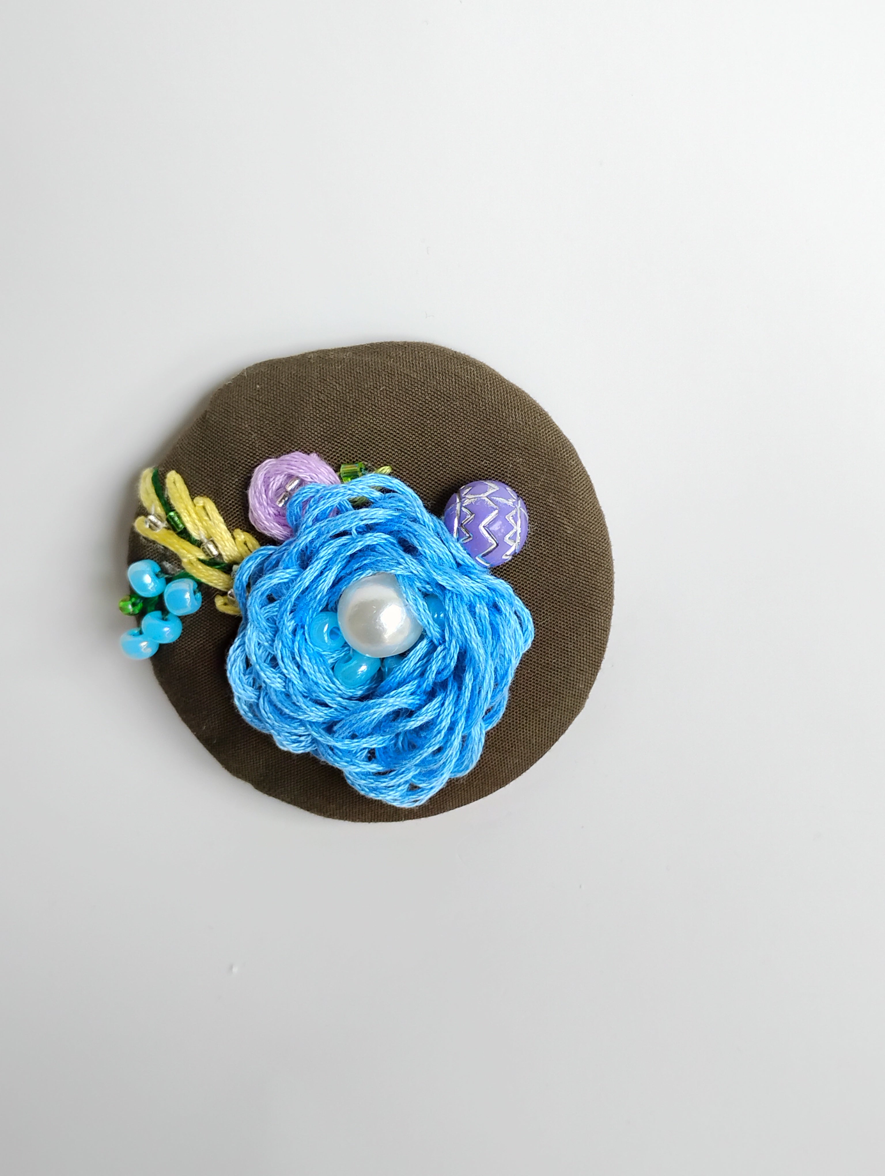 Decorative blue flower brooch on olive background