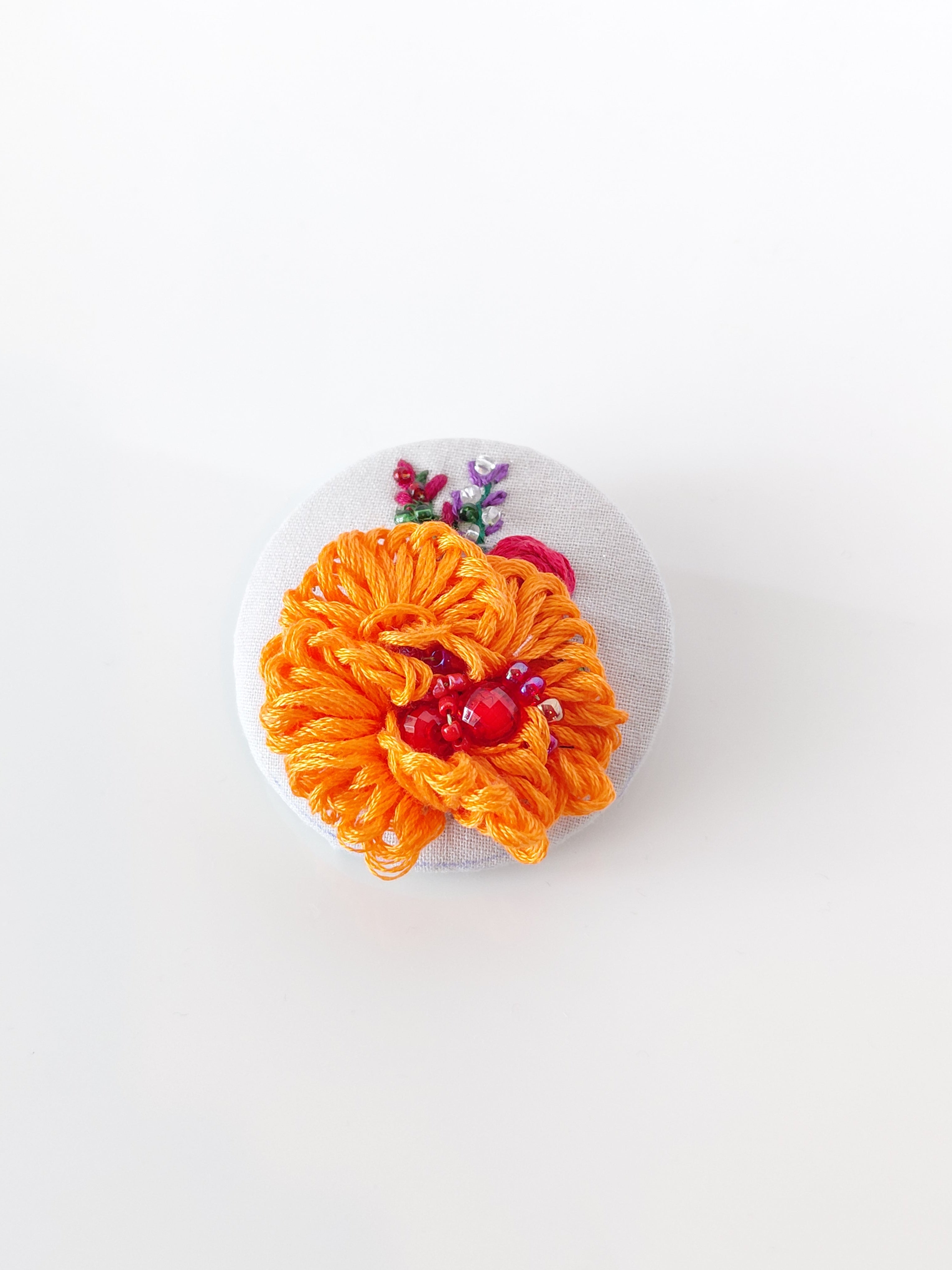 Decorative orange flower brooch on grey background