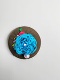 Decorative turquoise flower brooch on olive background