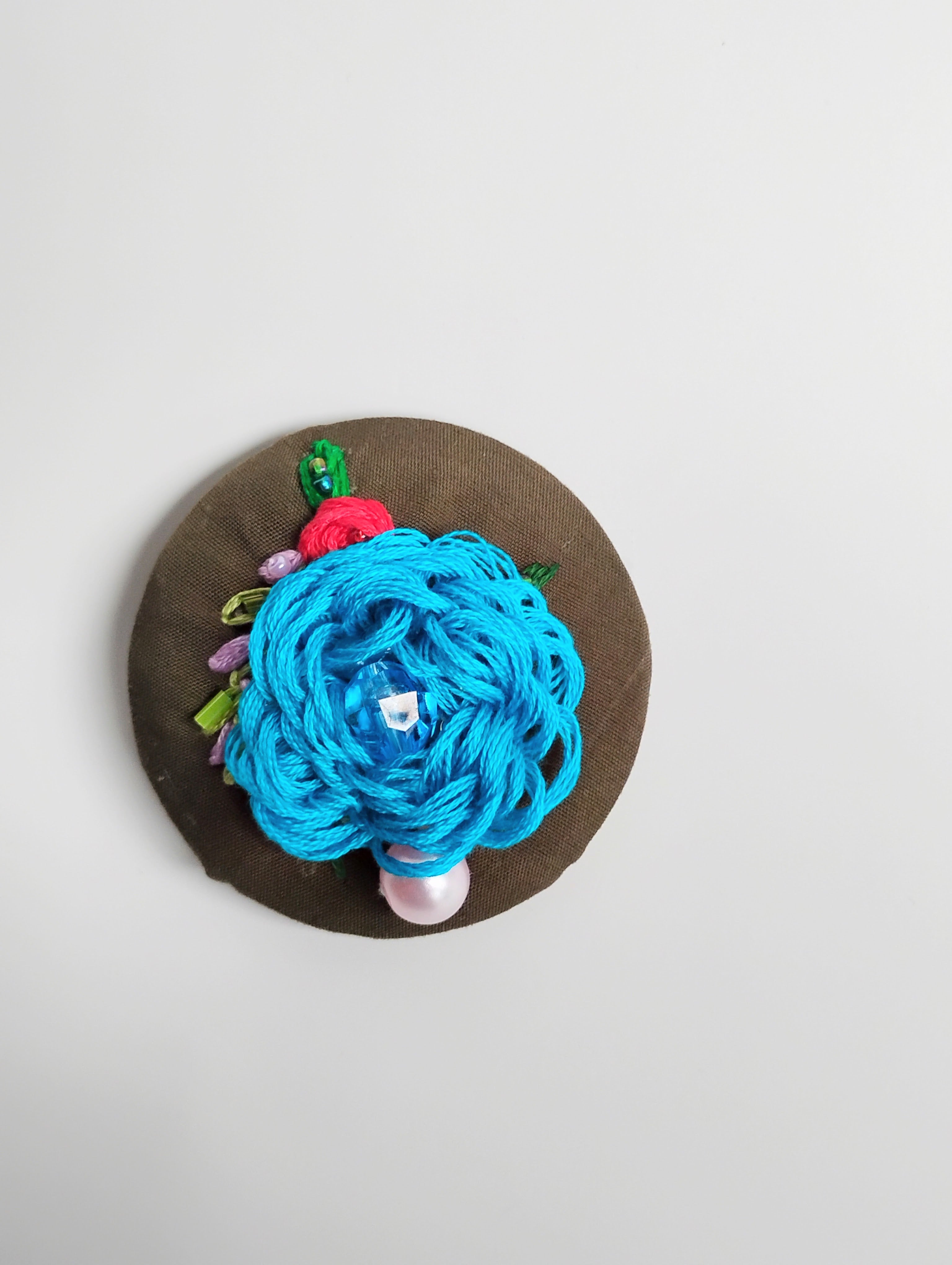 Decorative turquoise flower brooch on olive background